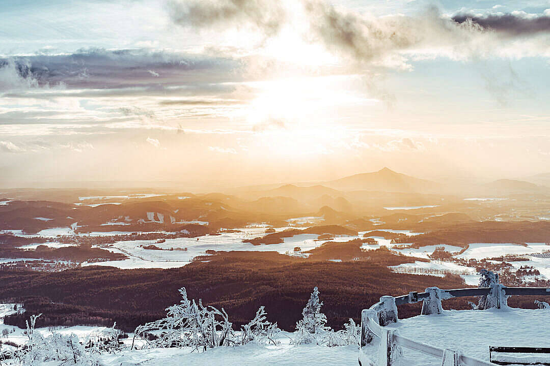 冬後山景免費PowerPoint背景 壁紙 — 陽光穿過雲層，照耀在廣闊的雪谷上，樹木覆蓋著霜，遠山連綿。