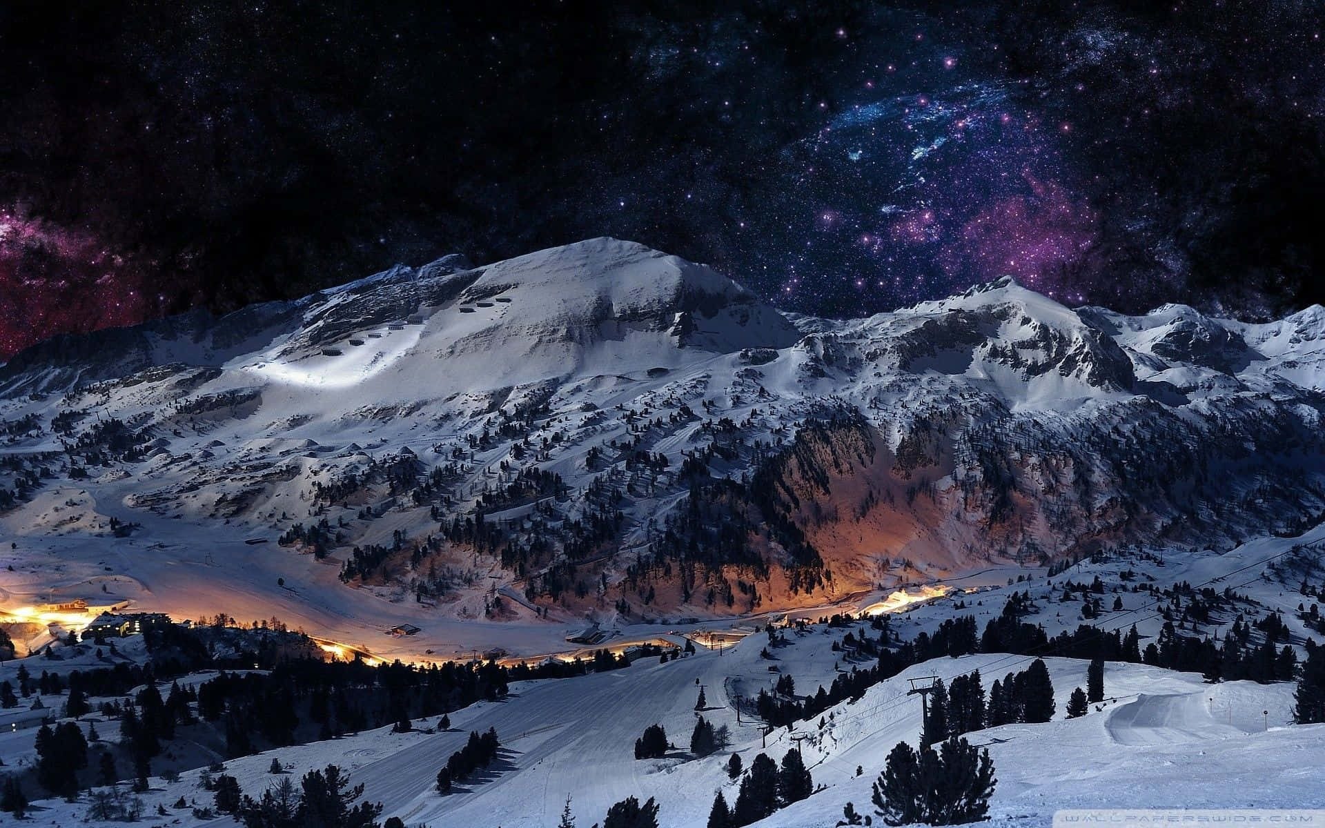 星空下的積雪山峰，下方有閃爍的村莊燈光。