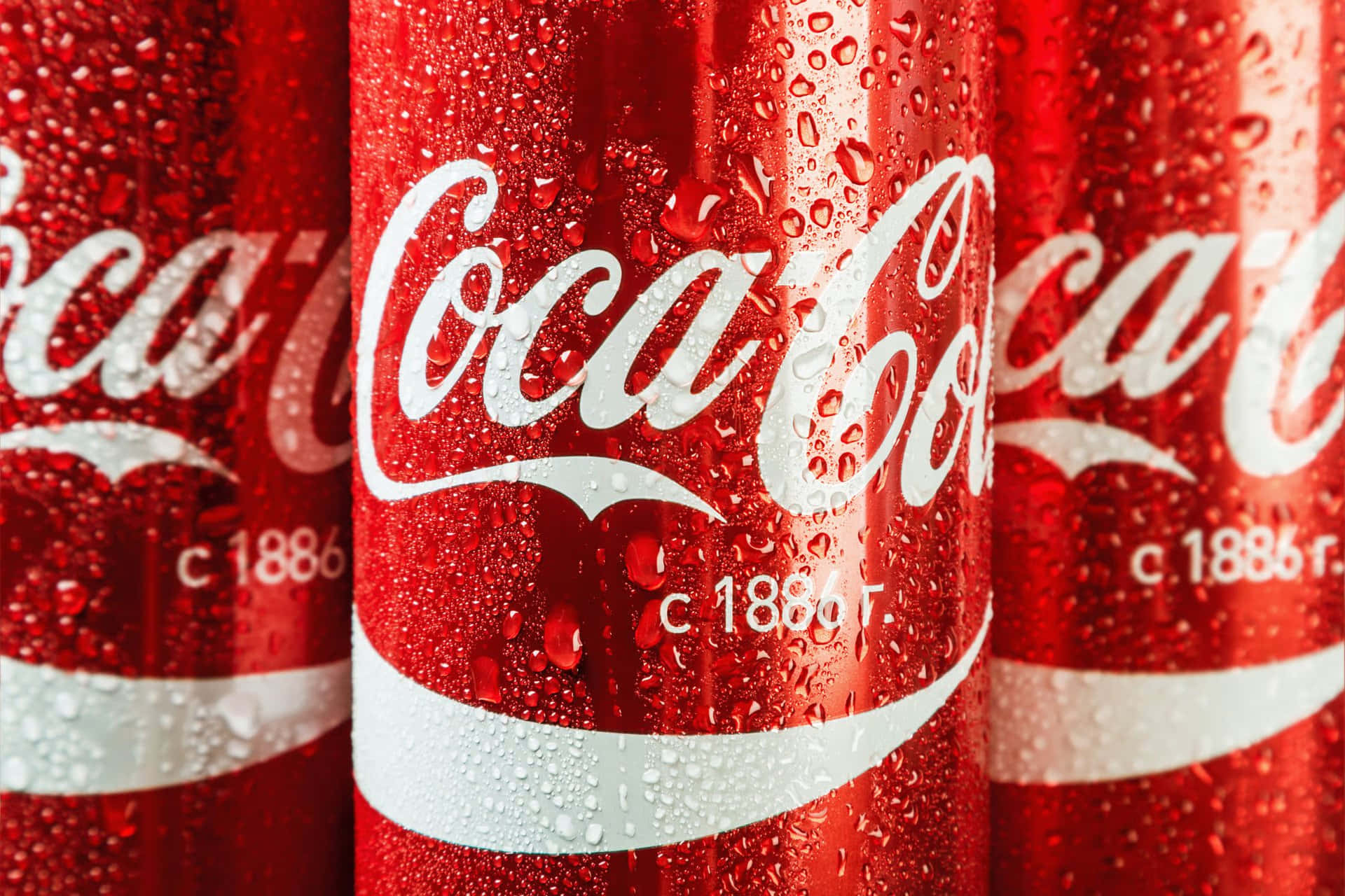 coca cola 桌布 壁紙 — 冰凍可口可樂罐的特寫，鮮紅色表面上凝結的水珠閃閃發光。