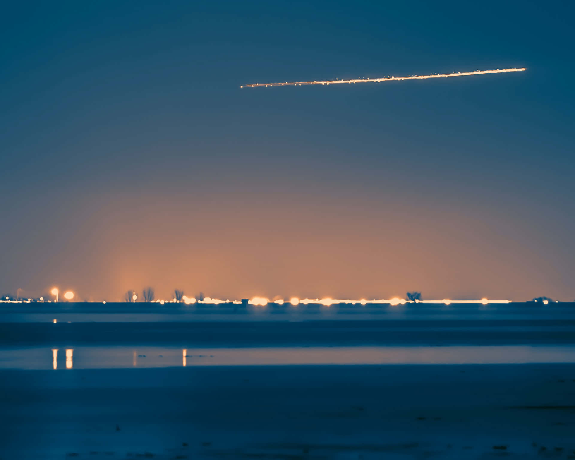comet 桌布 壁紙 — 冰凍湖面上寧靜的黃昏場景，發光的飛機尾跡劃過漸變的天空。