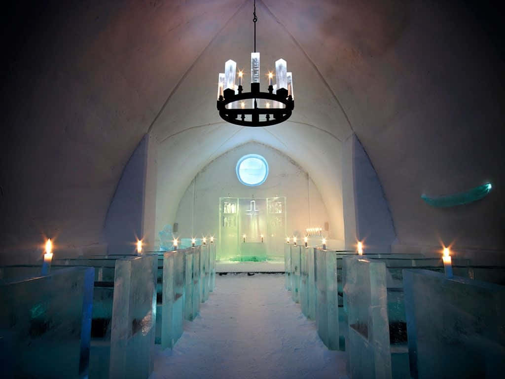 Ice Hotel 桌布 壁紙 — 冰教堂內部，拱形天花下，燭光與吊燈照亮半透明藍色長椅。