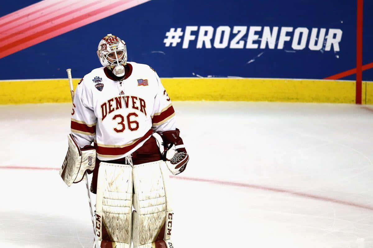 丹佛冰球守門員在 Frozen Four 錦標賽期間穿著栗色和白色裝備在冰場上。