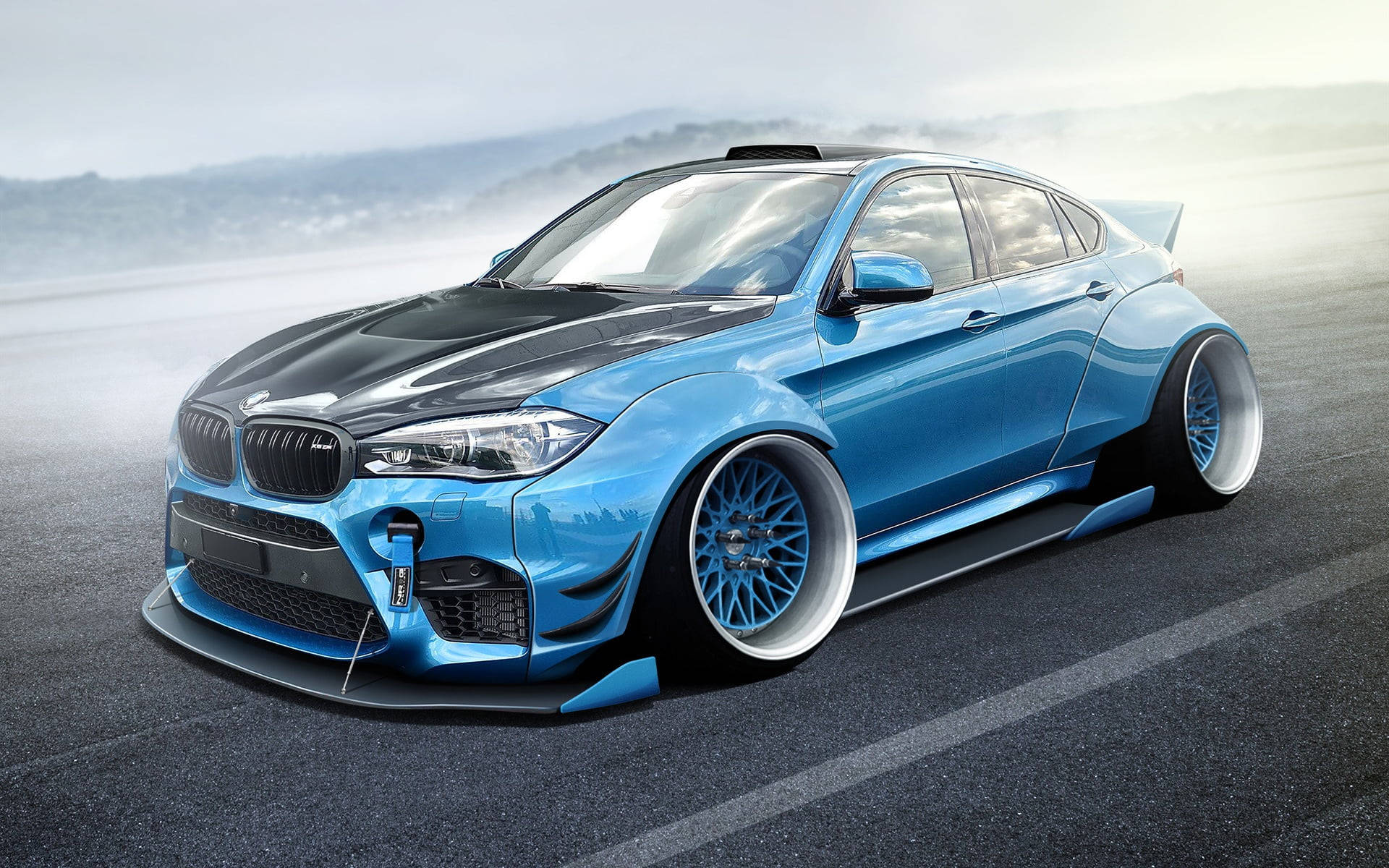 冰藍色豪華 BMW X6 M 壁紙 — 一輛時尚的藍黑改裝寶馬房車，配備定制輪圈和空氣動力學車身套件，停在霧氣瀰漫的瀝青路上。