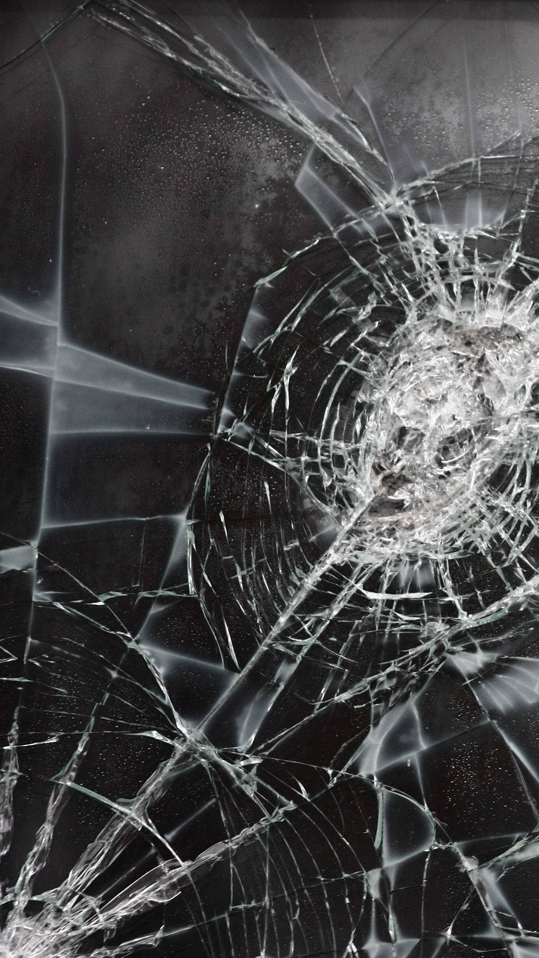 破碎的玻璃，裂紋從深色表面上的中心點擴散。