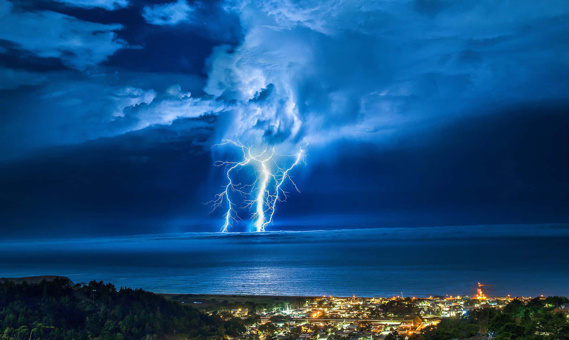 閃電照亮了沿海小鎮和海洋上空的暴風雨之夜。