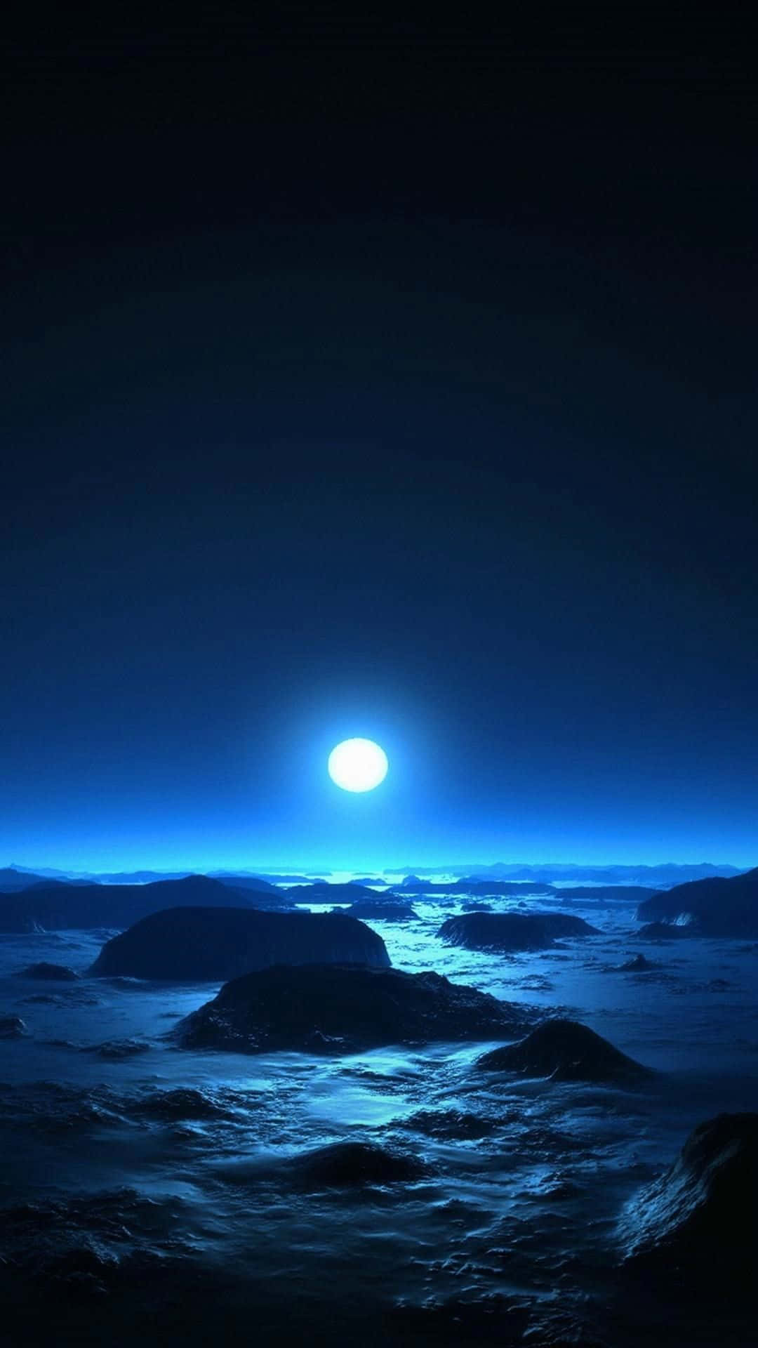 一輪明亮的月亮照亮了深藍色夜空下冰凍的岩石地形。