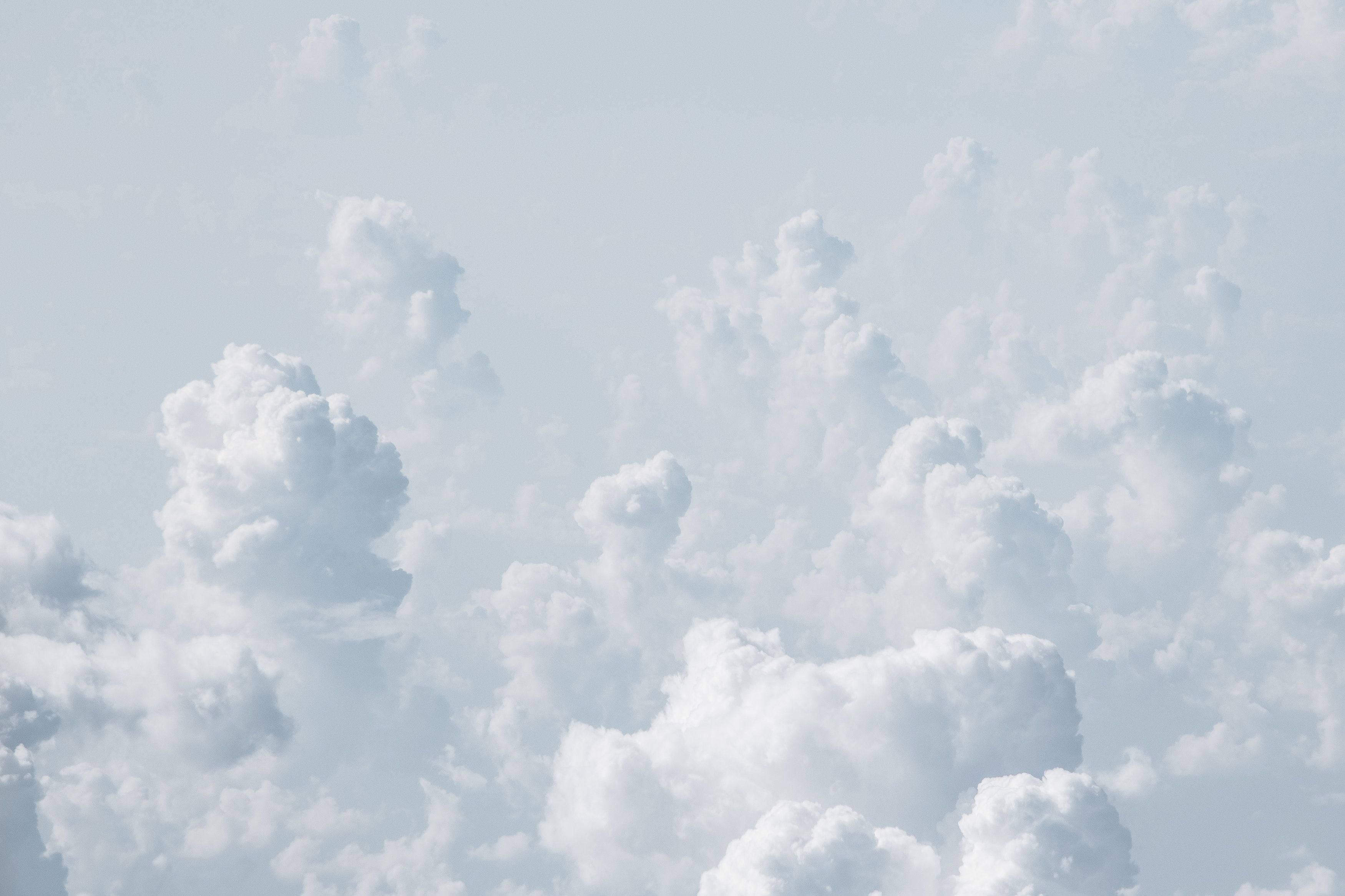 冷白色雲朵 壁紙 — 大片蓬鬆的白雲在淡藍色的天空中飄移，形成柔和空靈的圖案。