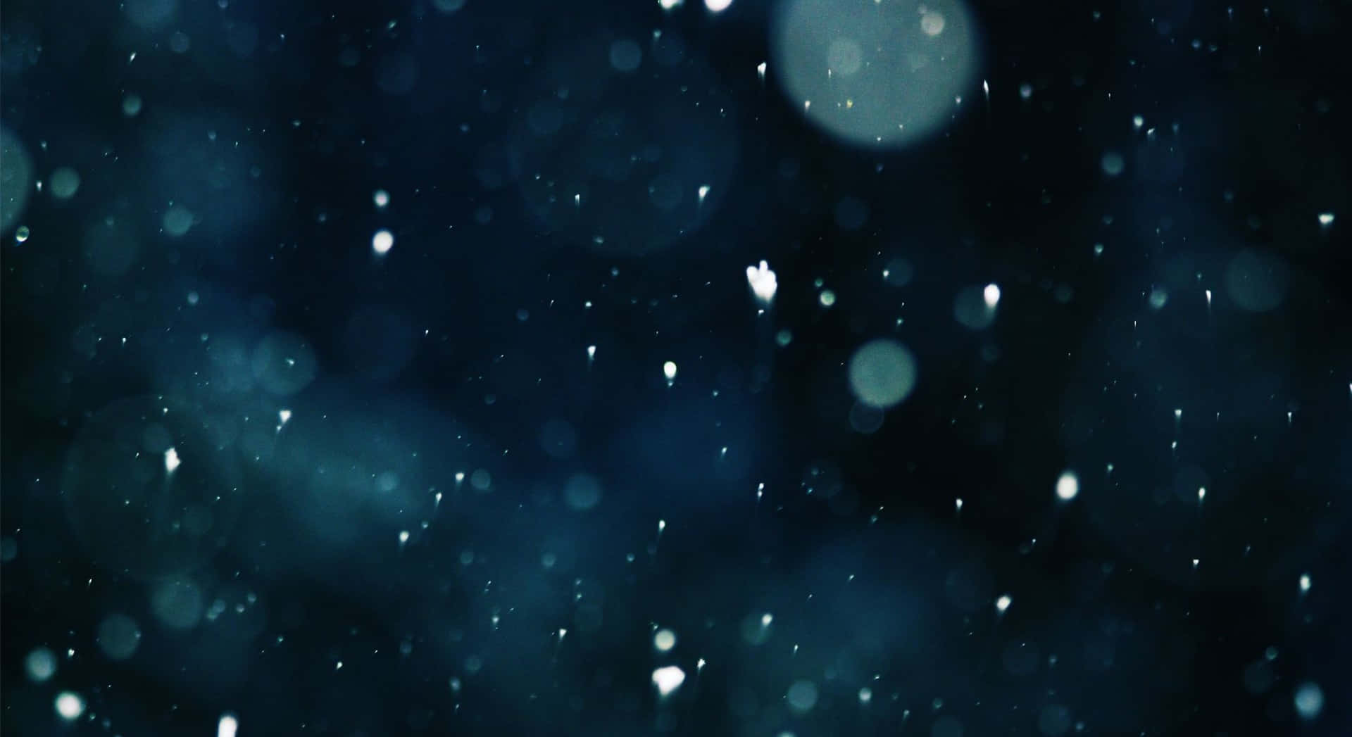 雪花在深藍色散景中飄落，伴隨著發光球體和光粒子。