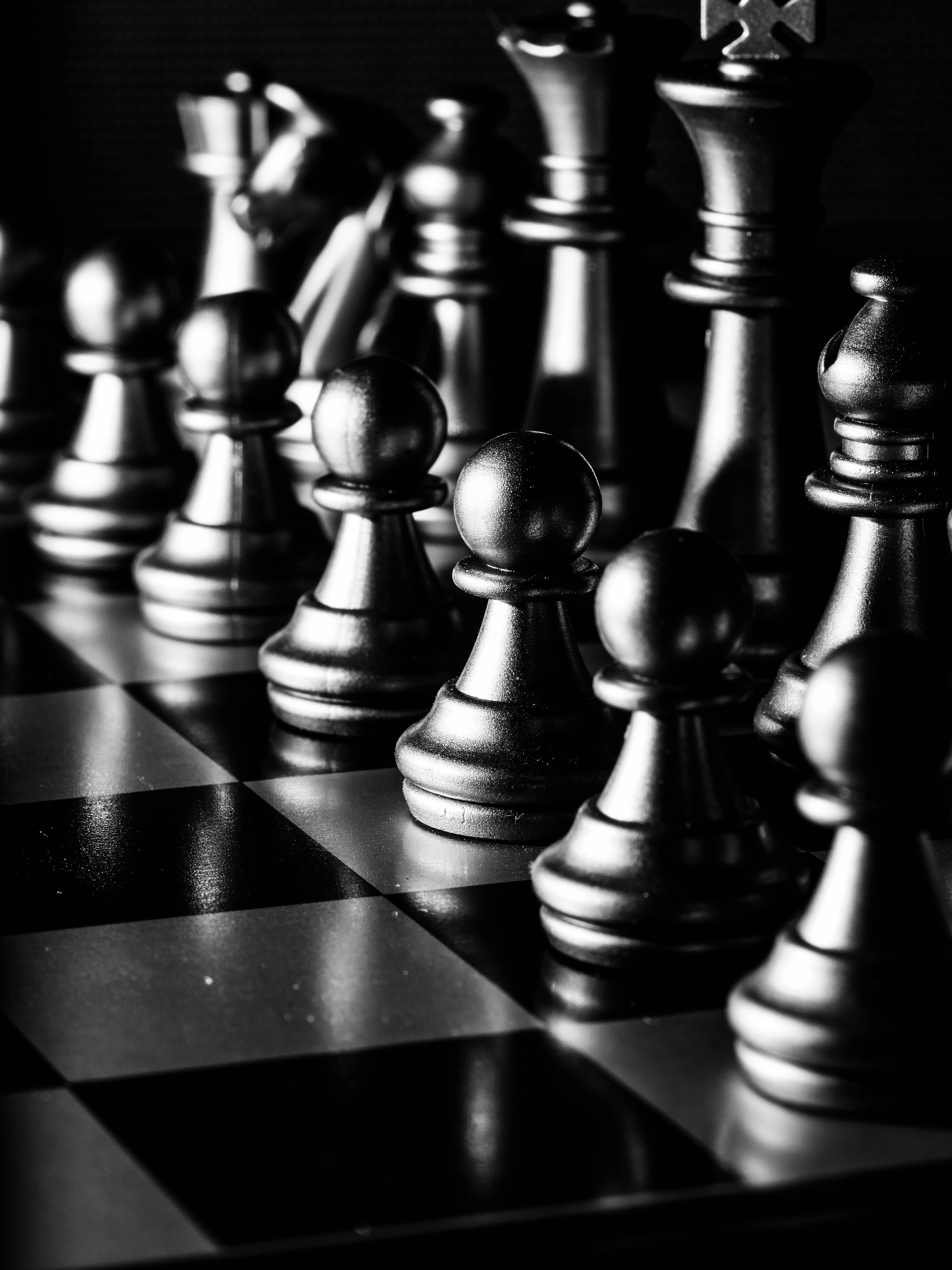 冷調美學單色棋盤 壁紙 — 黑白特寫金屬國際象棋棋子排列在棋盤上，景深較淺。