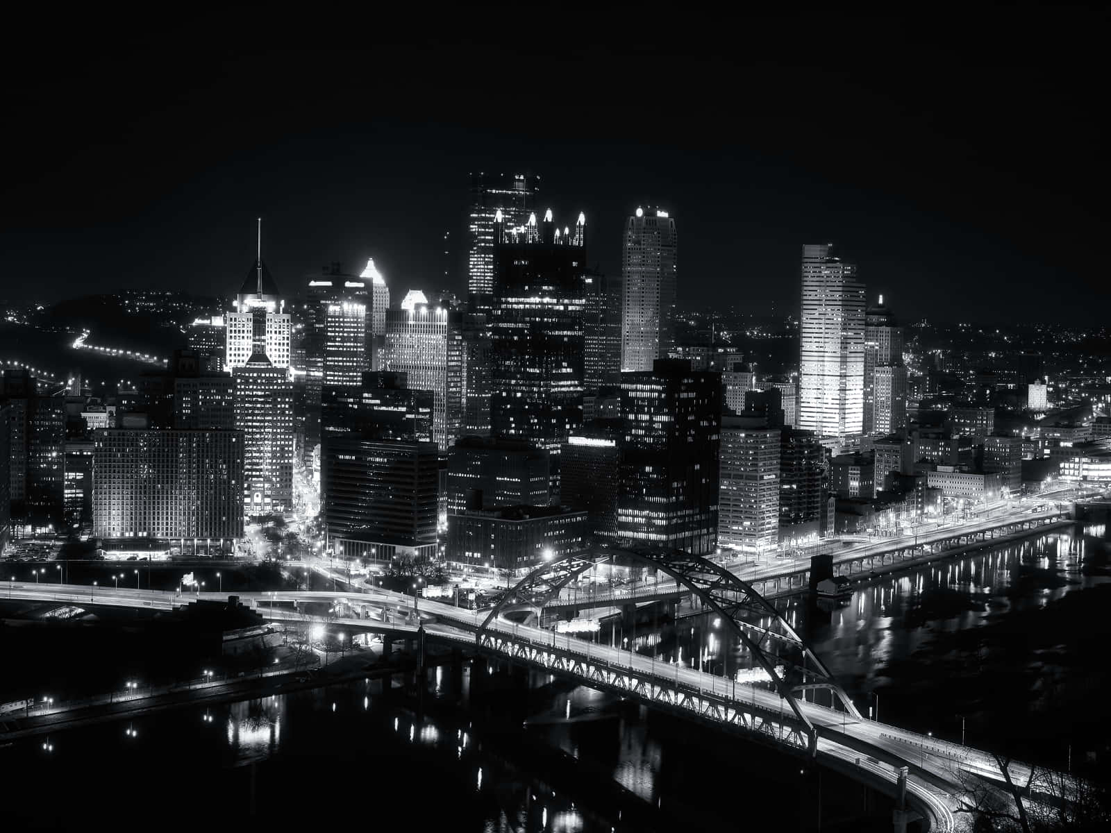 黑白夜景城市景觀，水面上的發光建築和橋樑。