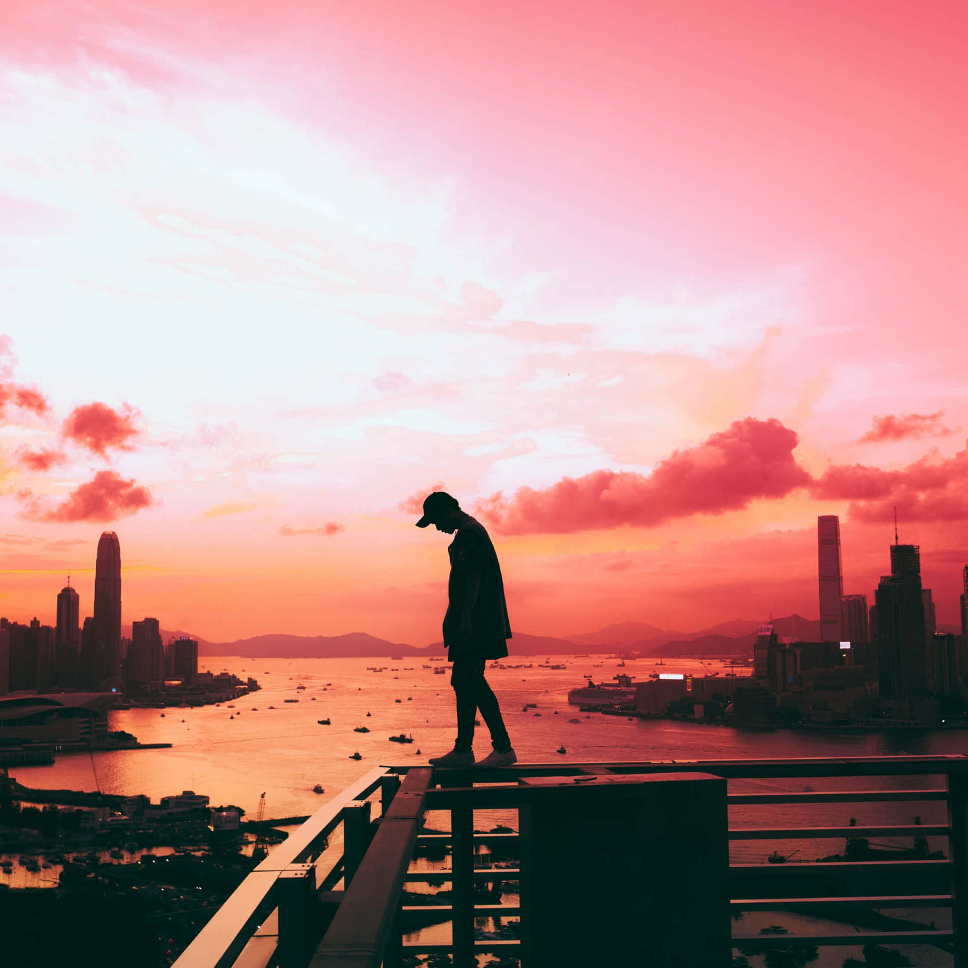 人站在欄杆上看海港城市的日落