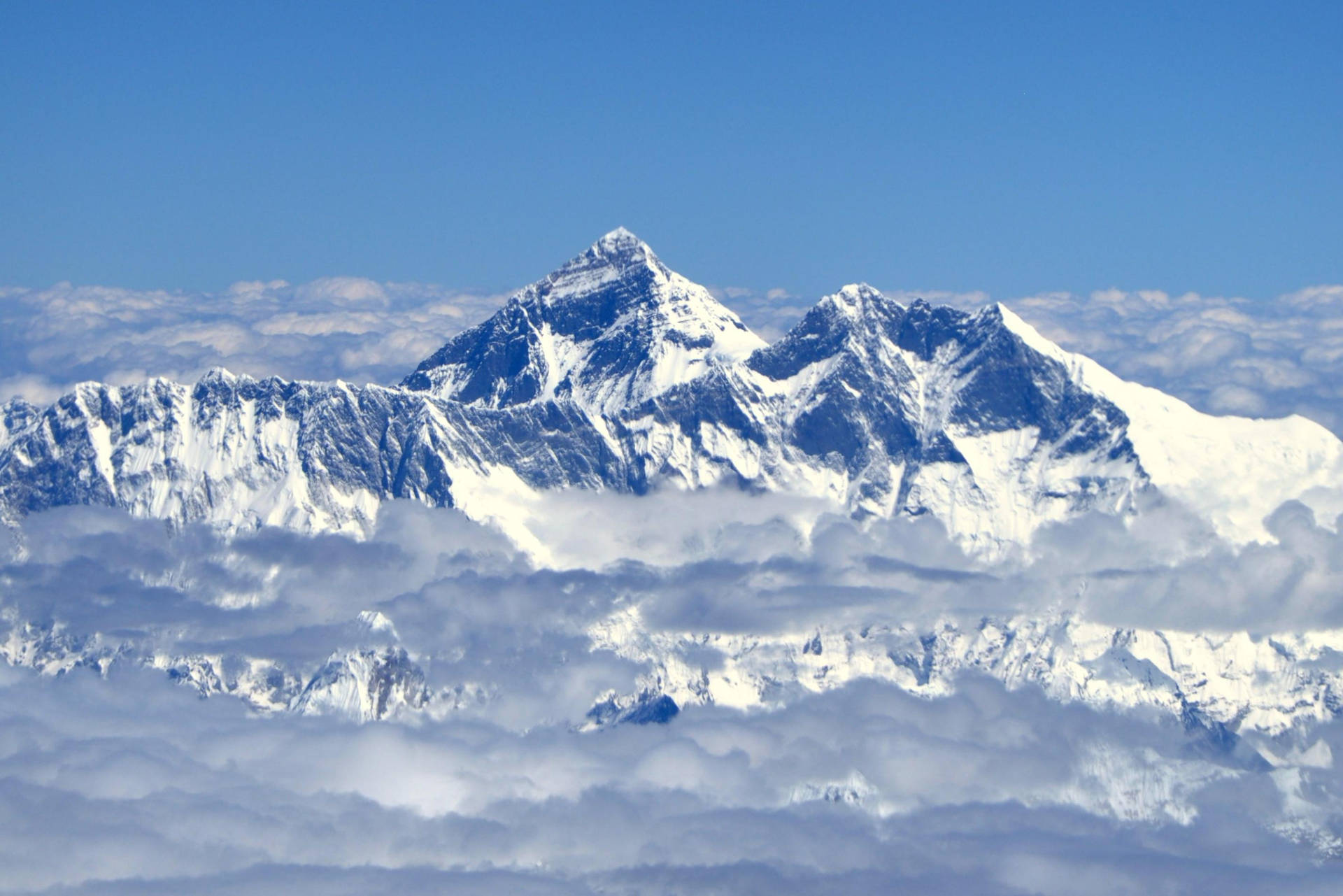 凝視珠穆朗瑪峰的壯麗風景 壁紙 — 白雪覆蓋的山峰在清澈的藍天下穿過雲海。