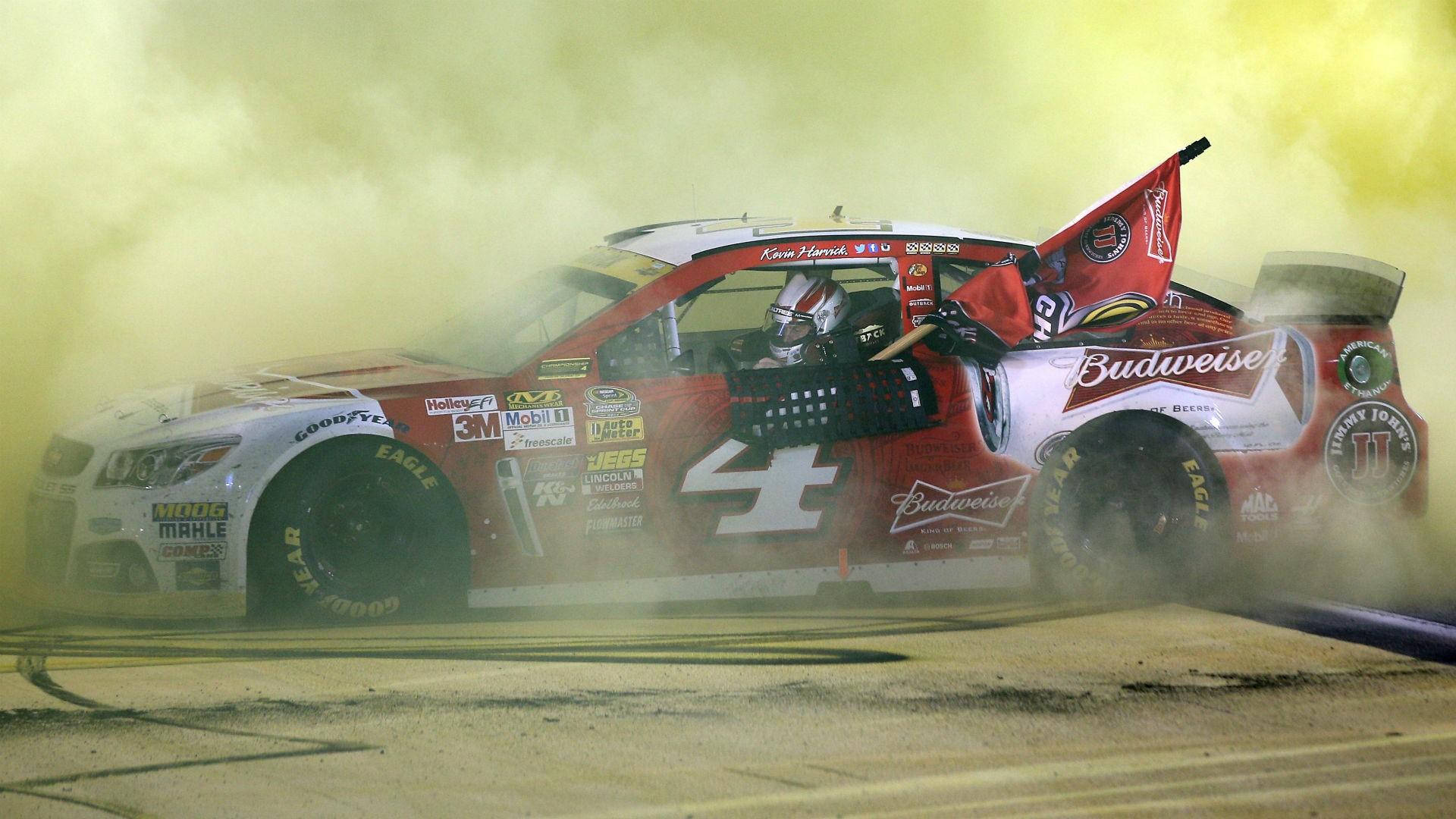 NASCAR賽車號碼4在夜間泥地上以煙霧和旗幟慶祝勝利。