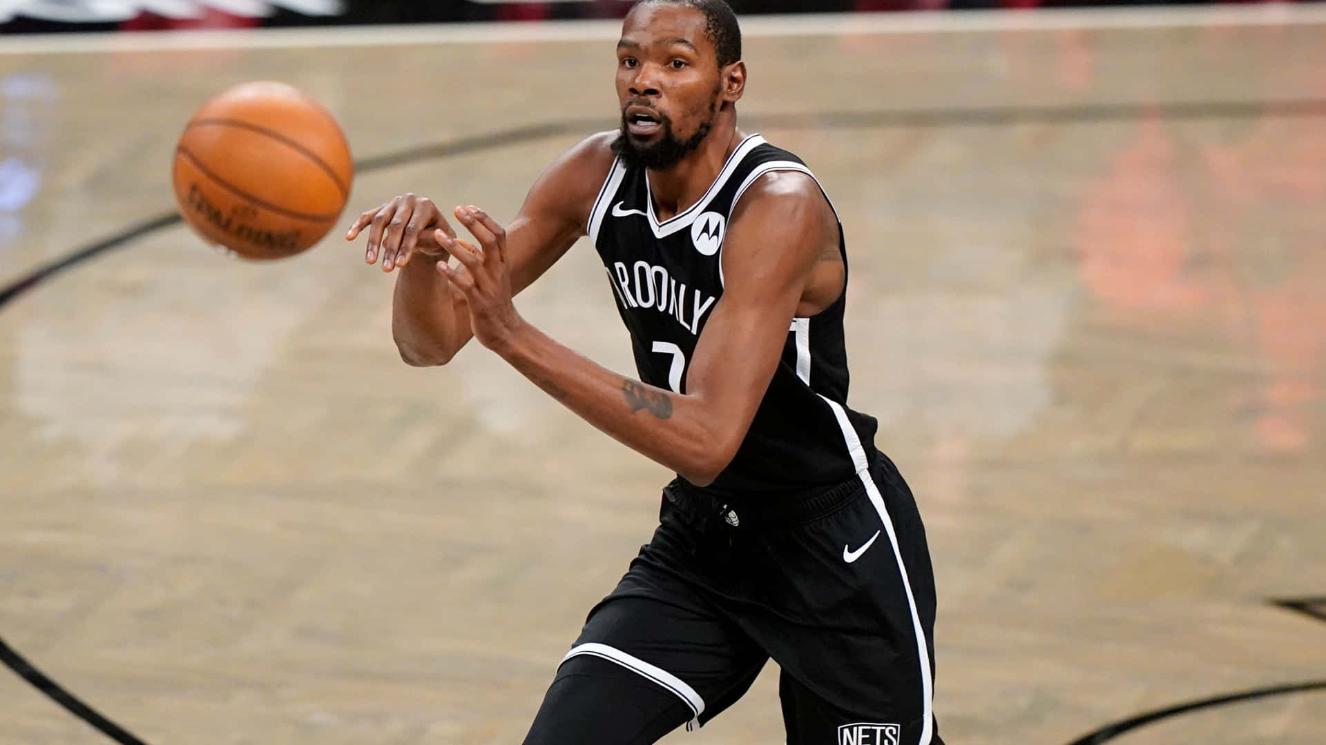 職業籃球運動員身穿黑色布魯克林籃網隊球衣在比賽中運球。