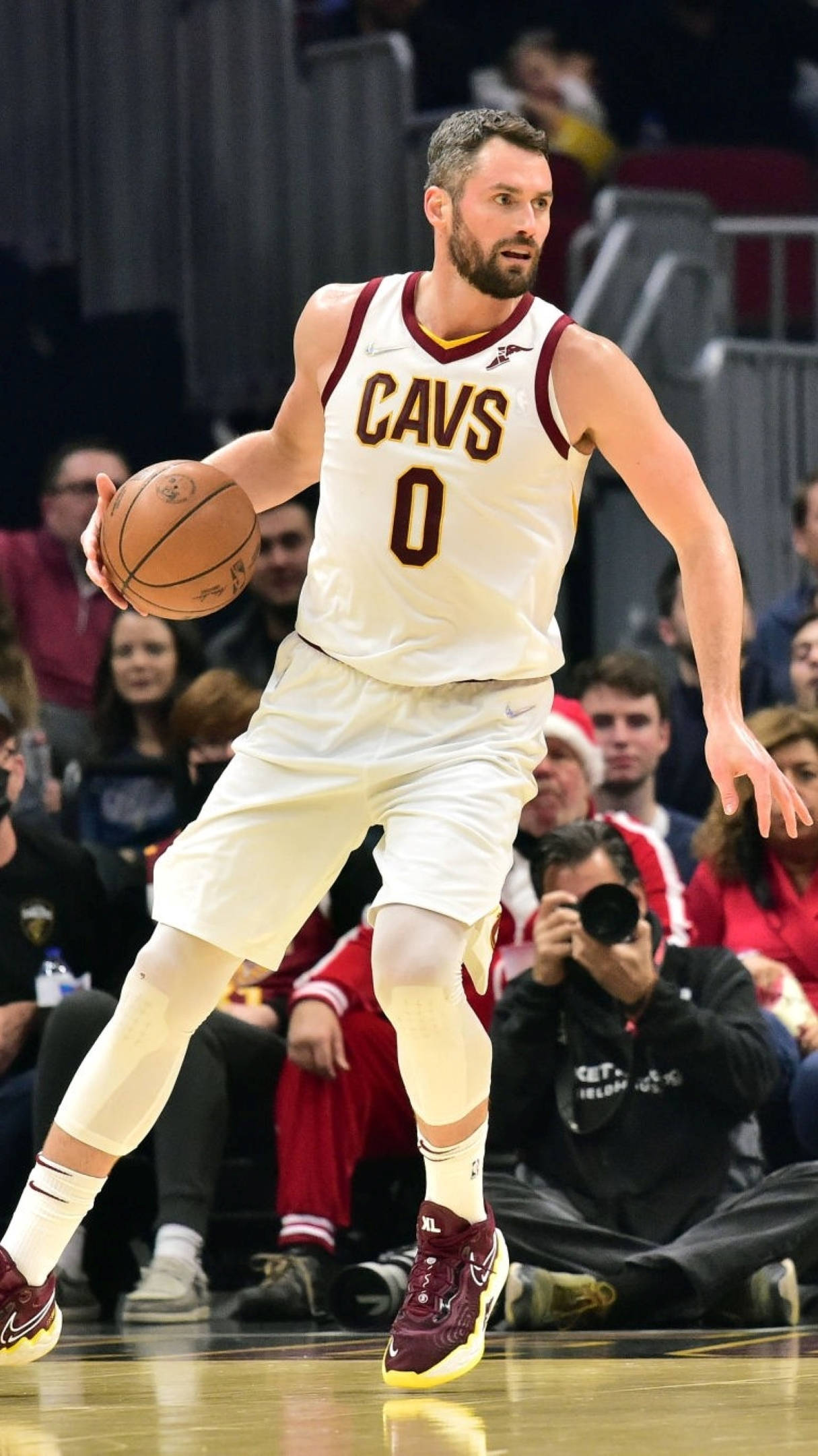 凱文·樂夫克里夫蘭騎士隊比賽 壁紙 — 一名身穿白色 Cavs 球衣的籃球運動員在比賽中運球，背景有觀眾。