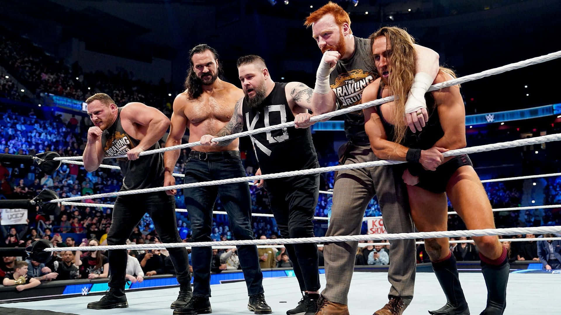 凱文·歐文斯 WWE 生存者戰爭遊戲 壁紙 — 五位肌肉發達的摔角手在擠滿觀眾的場館中，於一場激烈的WWE比賽中用力拉著繩索。