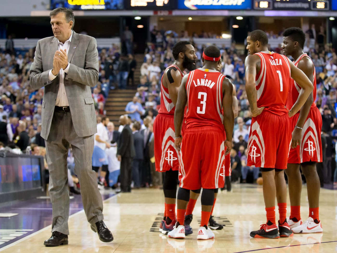 凱文·麥克海尔2015年NBA西區決賽後回座 壁紙 — 一位身穿灰色西裝的籃球教練在比賽期間為身穿紅色球衣的球隊在球場上圍攏而鼓掌。