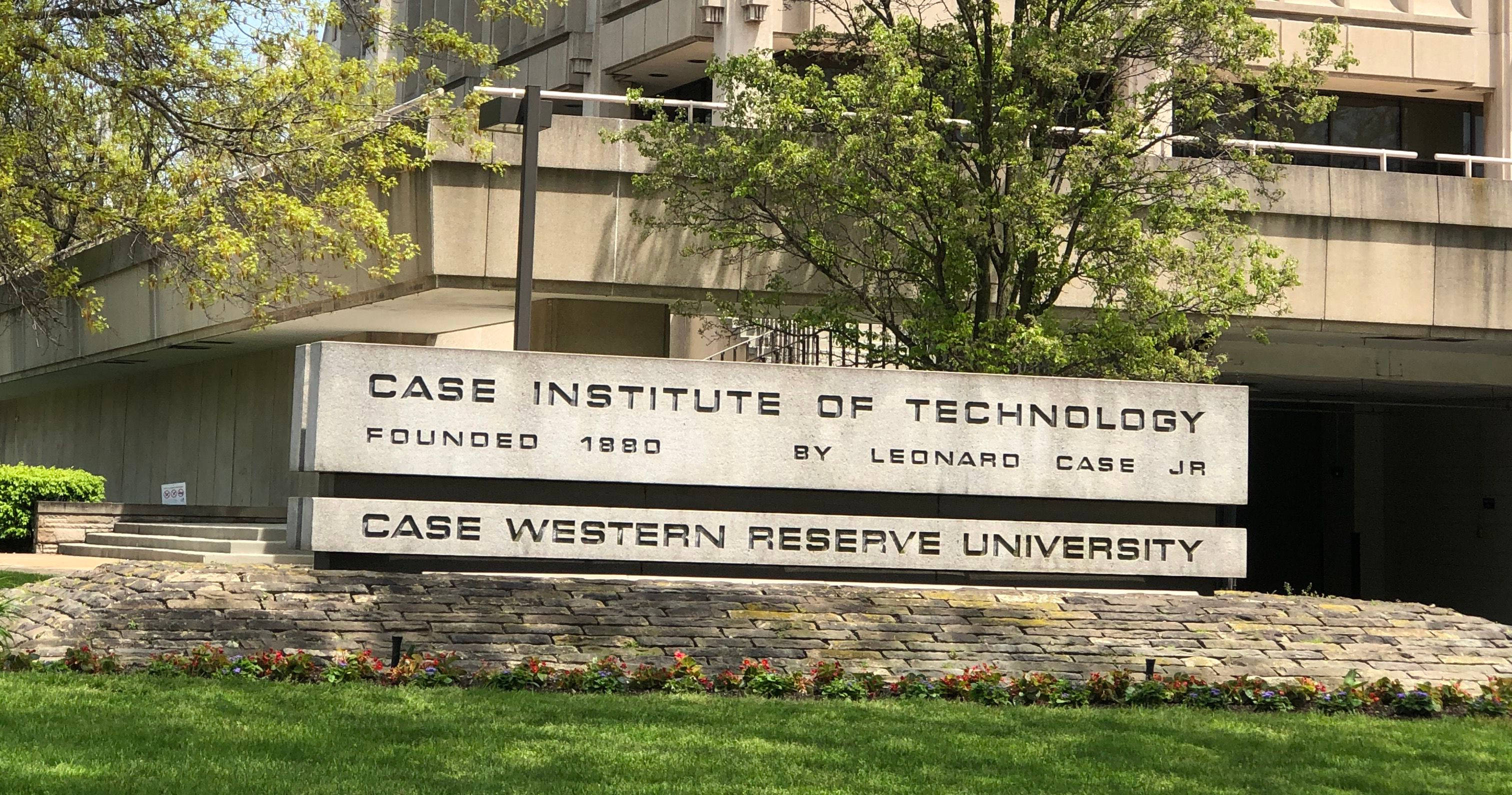 凱斯西儲大學理工學院入口 壁紙 — 一個為凱斯理工學院和凱斯西儲大學而設的石製標誌，矗立在一座現代建築前，周圍有綠樹和草地，在明亮的日光下。