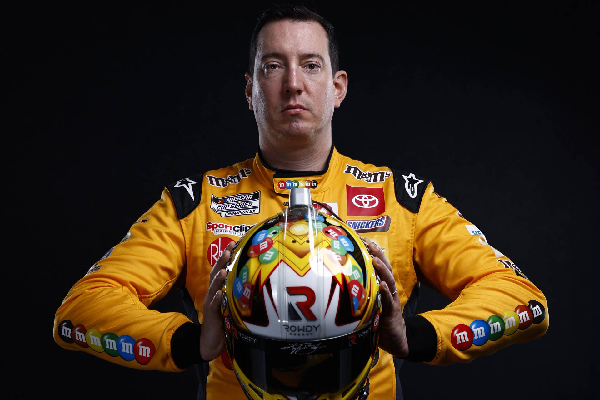 NASCAR車手在攝影棚中手持M&M's主題賽車頭盔。