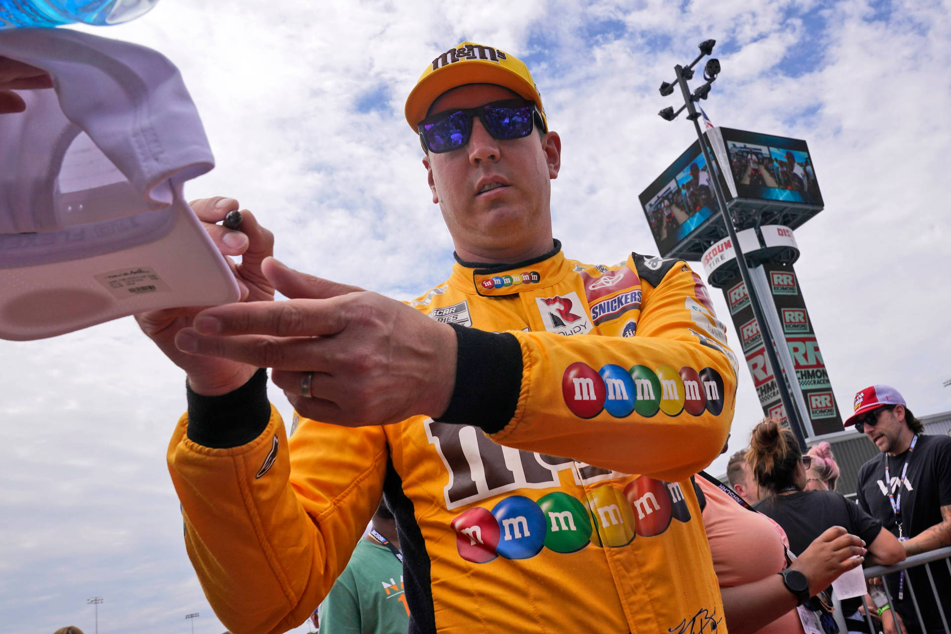 NASCAR車手在賽道上為粉絲簽名帽子。