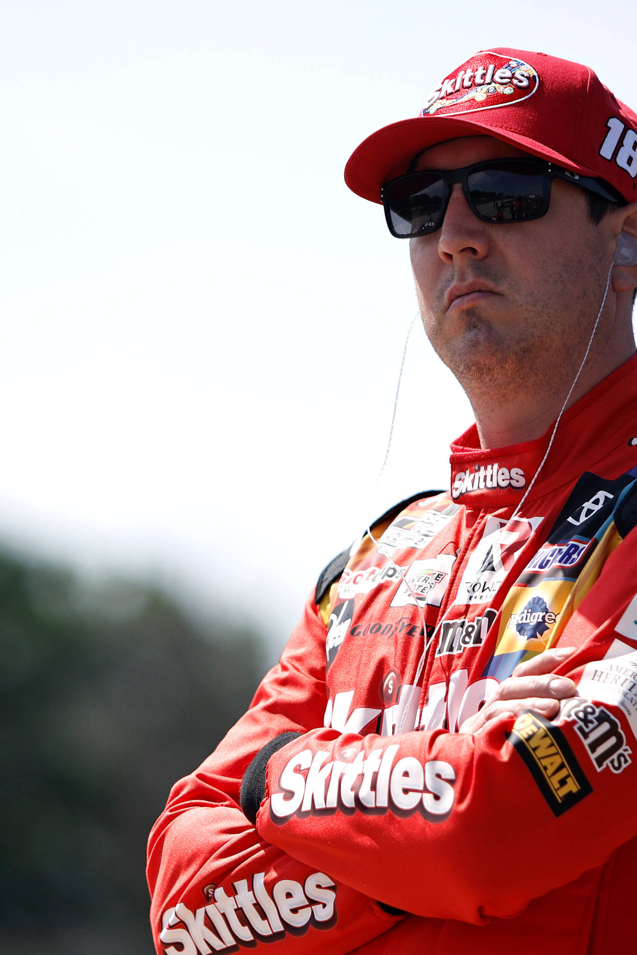 身穿紅色Skittles制服的NASCAR車手在戶外交叉雙臂。