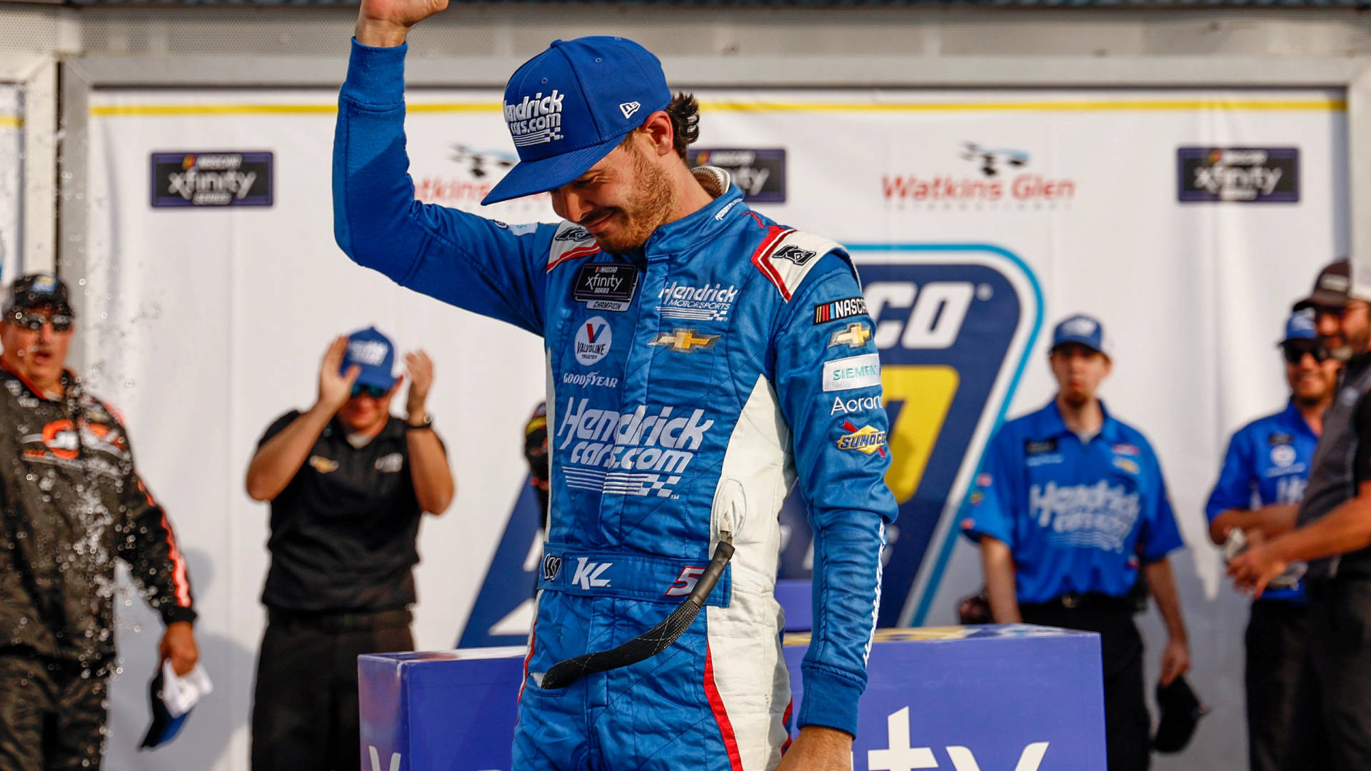 NASCAR車手在頒獎台上以香檳噴霧和車隊慶祝勝利。