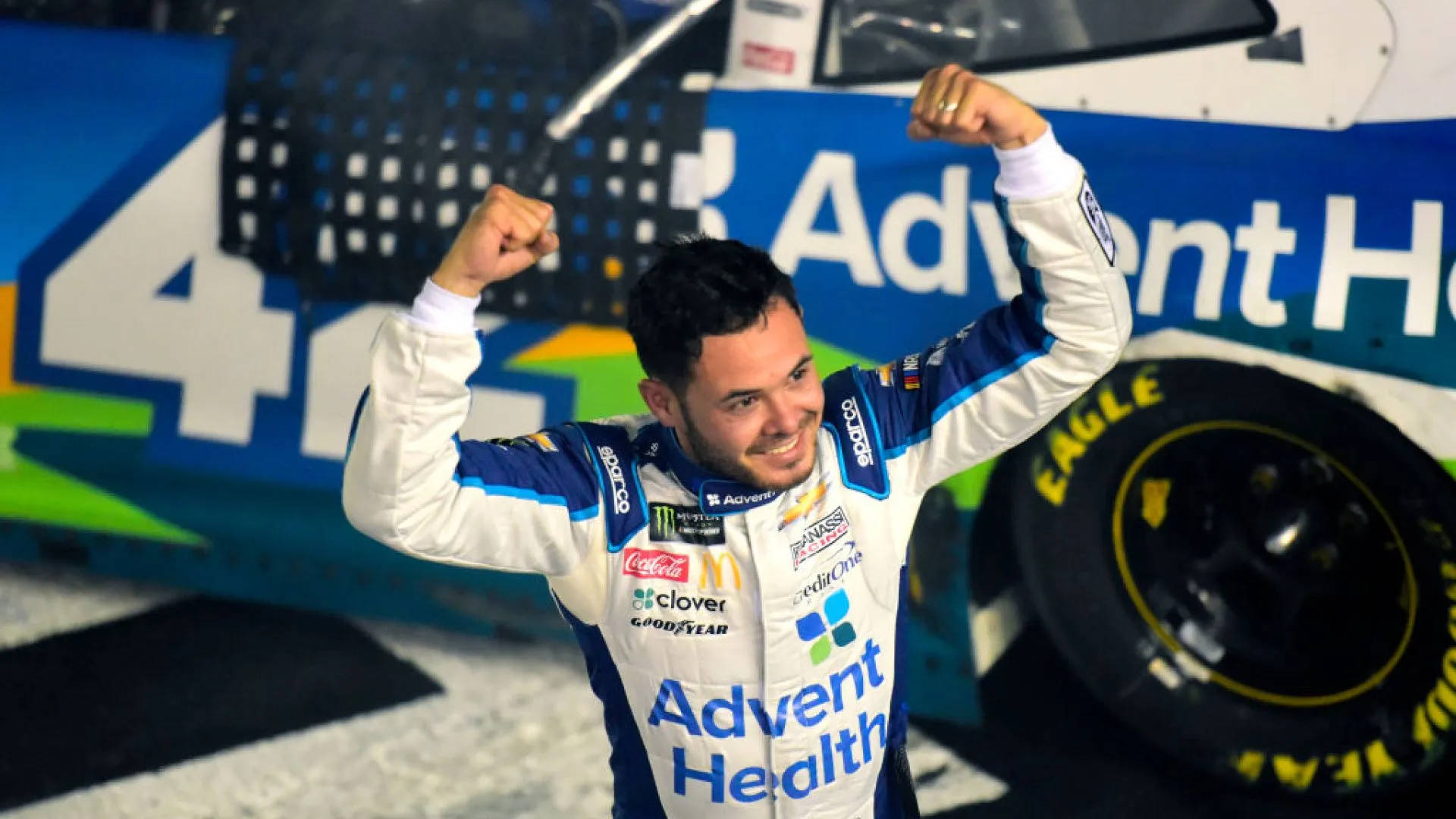 NASCAR車手在賽車旁舉起拳頭慶祝勝利。