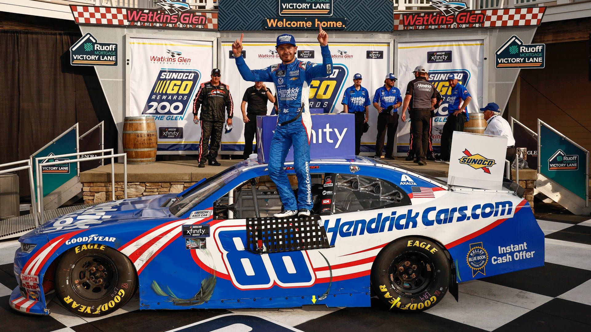 NASCAR車手在沃特金斯格倫的勝利車道上在賽車頂上慶祝勝利。