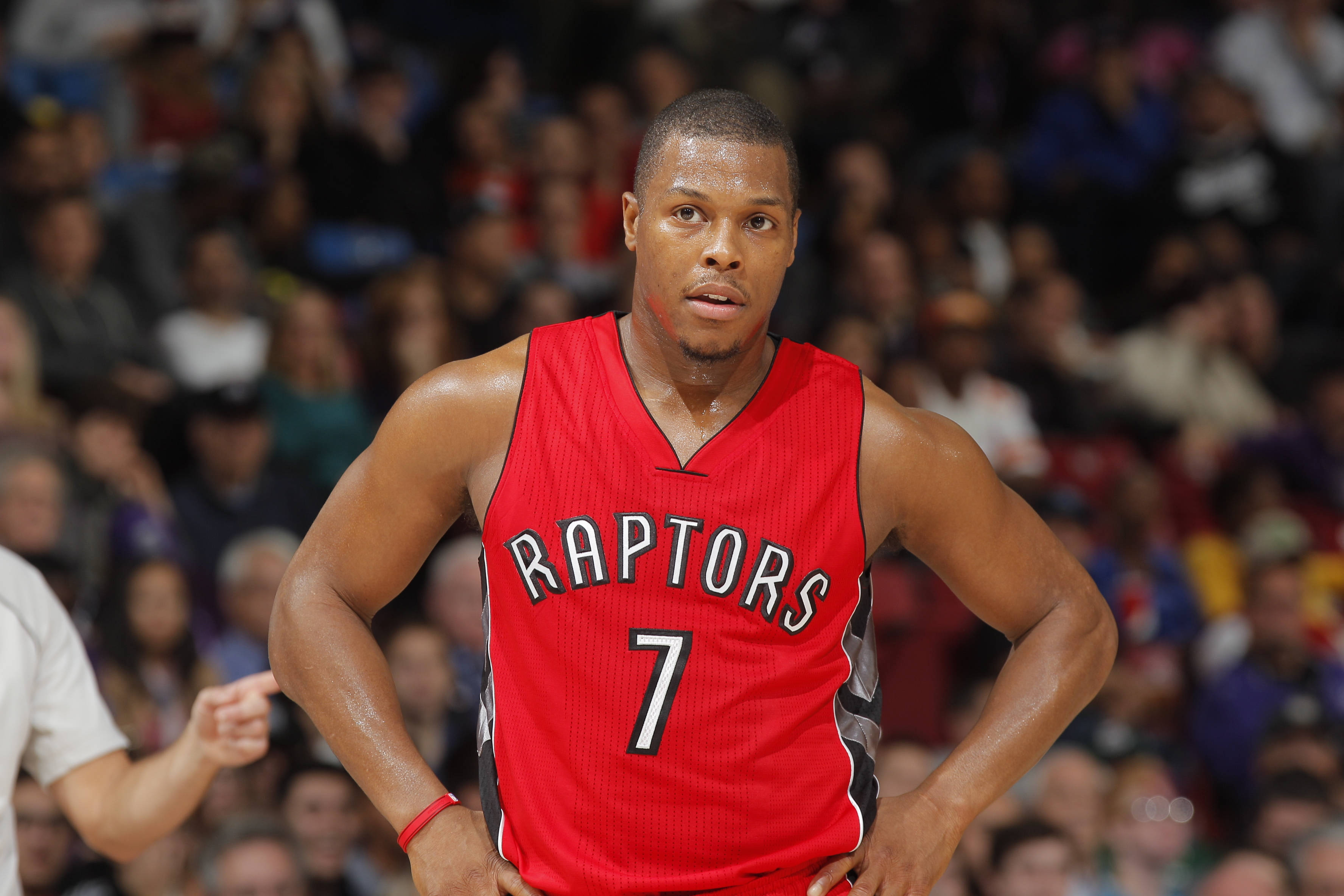 凱爾·洛瑞超高清 壁紙 — 一位專注的籃球運動員穿著紅色Raptors球衣，在比賽中雙手叉腰站立，身後是模糊的人群。