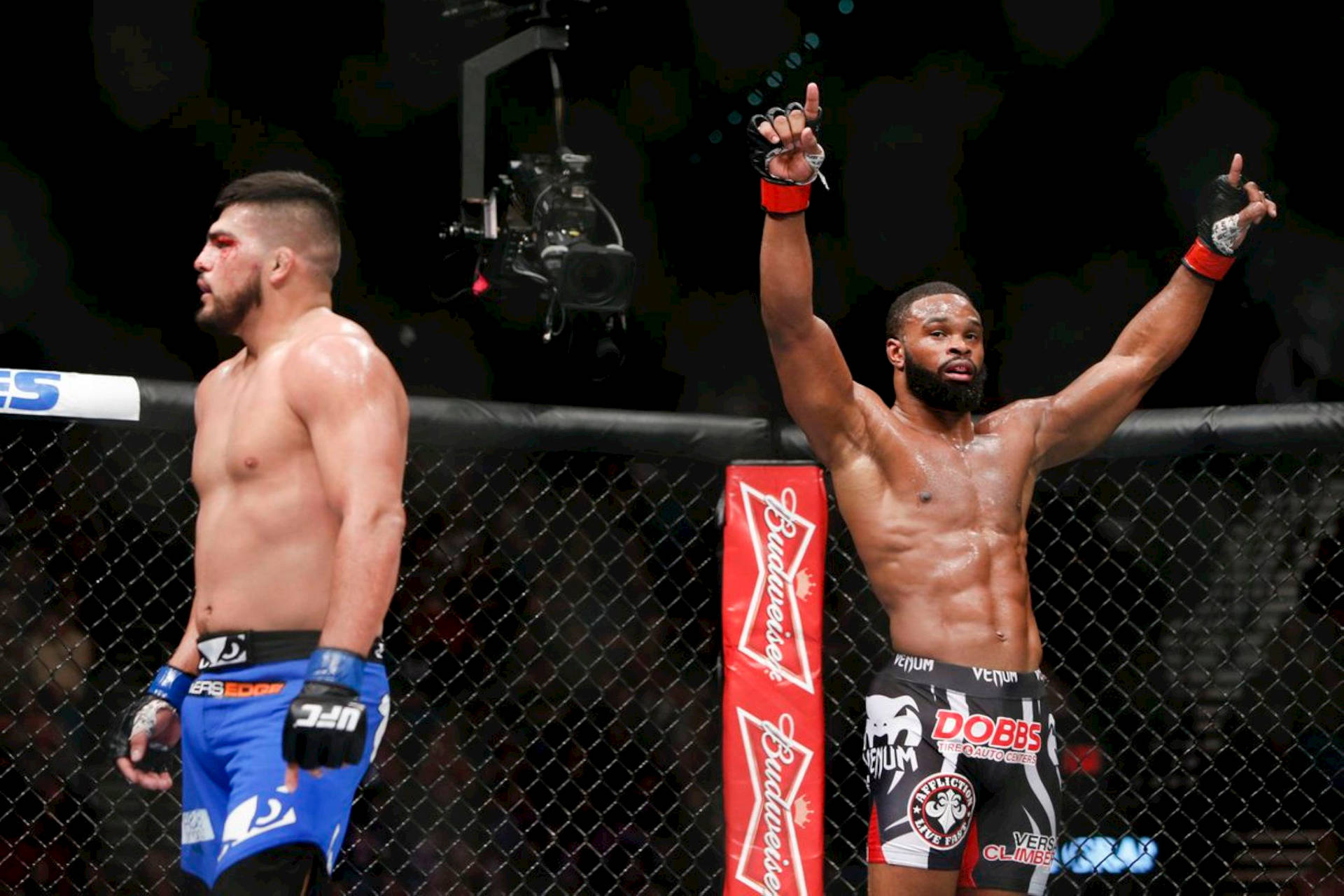 八角籠內兩名MMA拳手，一名勝利高舉雙臂，另一名在場館燈光下垂頭喪氣地站着。
