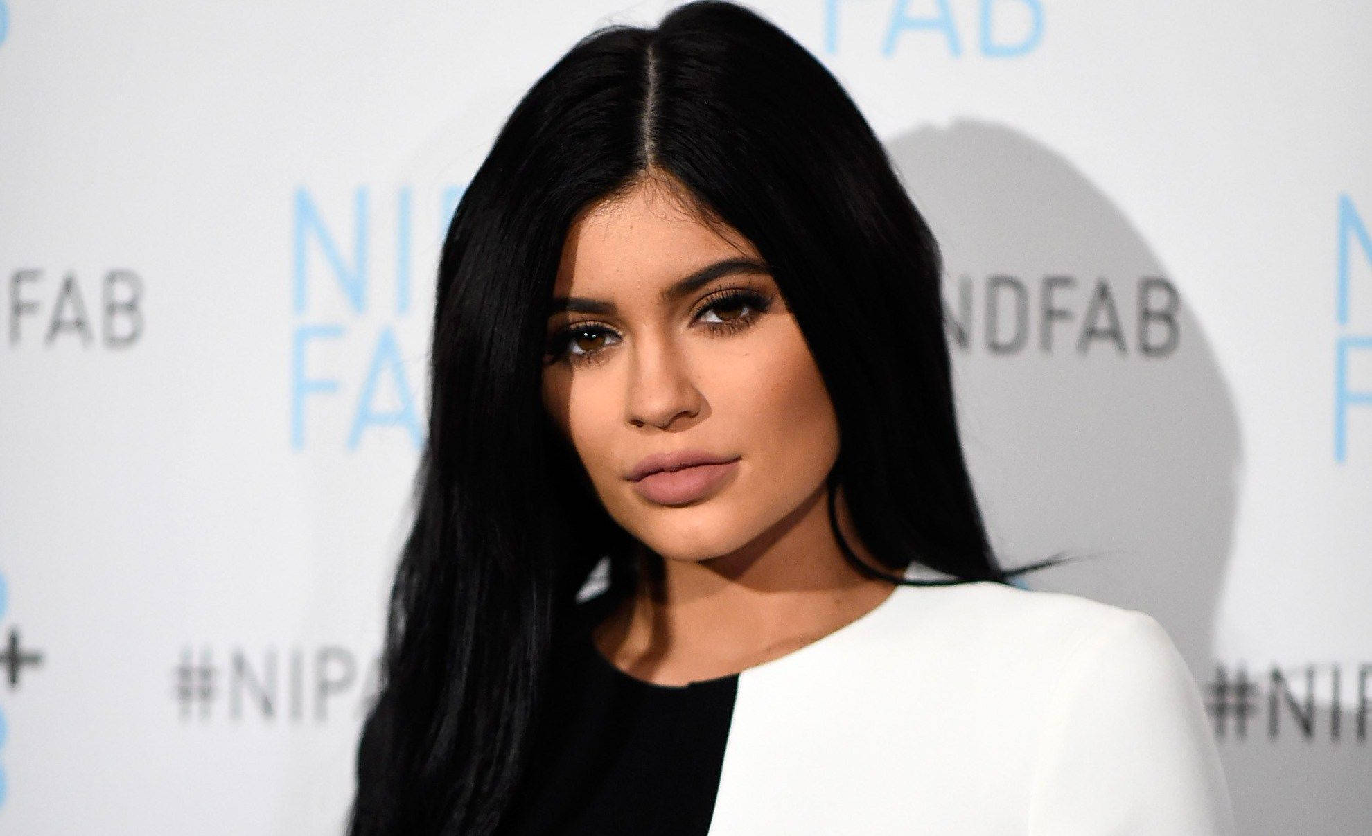 凱莉·詹娜Nip Fab造型 壁紙 — Kylie Jenner 喺品牌活動背景前自信地擺姿勢，身穿黑白套裝。