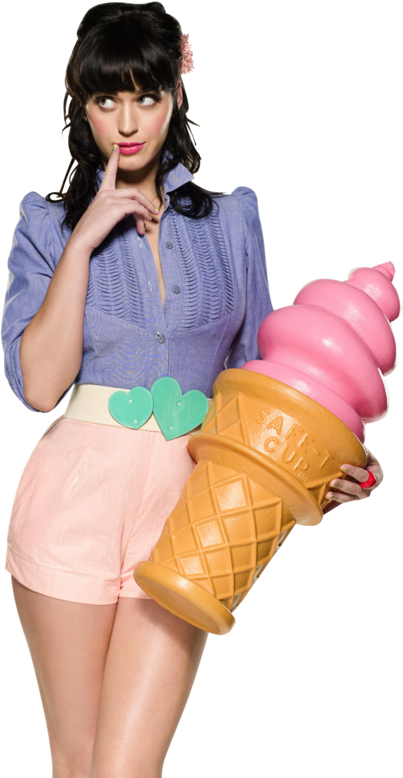 凱蒂·佩里手持巨型冰淇淋錐 壁紙 — 一位身穿藍色襯衫和粉紅色短褲的女性，手持一個巨大的粉紅色冰淇淋甜筒，同時俏皮地觸摸嘴唇。
