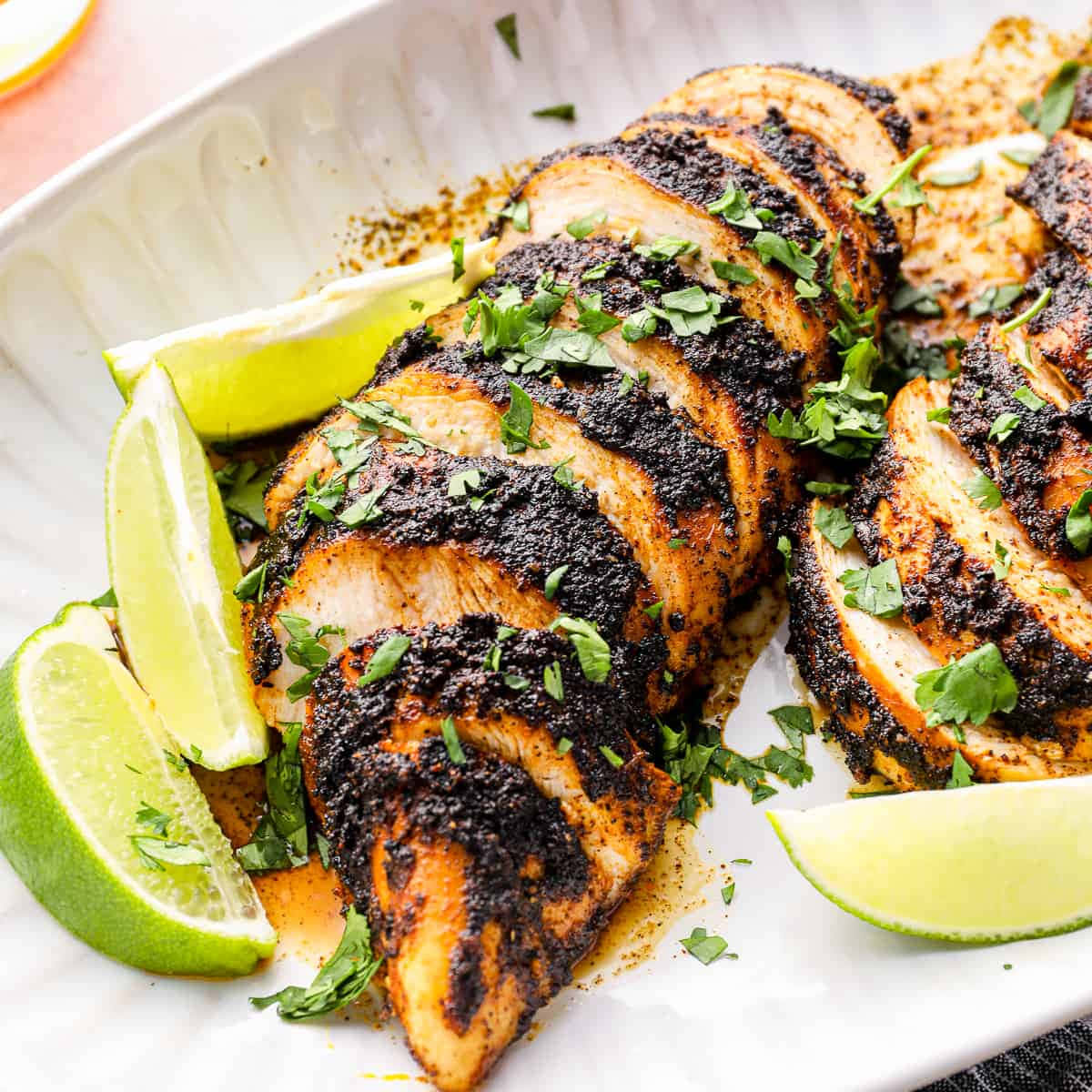 Blackened Chicken 桌布 壁紙 — 切片燒雞配深色香料擦和新鮮芫荽，飾以青檸角，盛於白碟上。