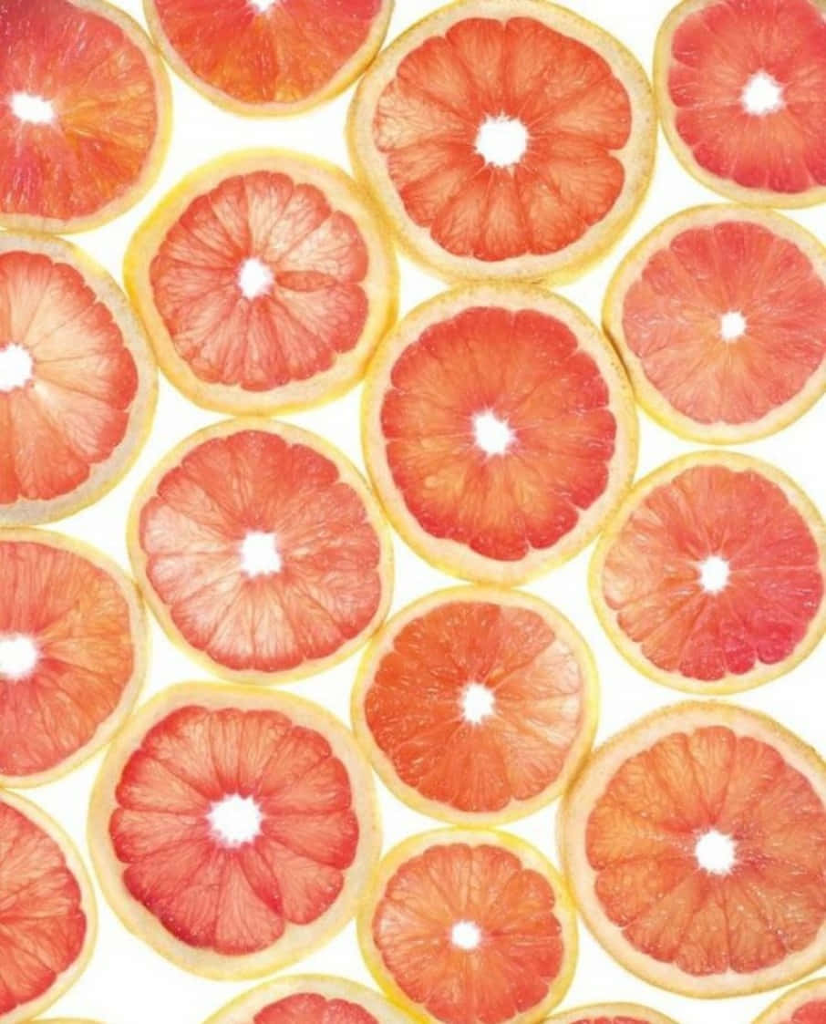 Pink Grapefruit 桌布 壁紙 — 切片西柚以鮮豔的圓形圖案排列在明亮的白色背景上。
