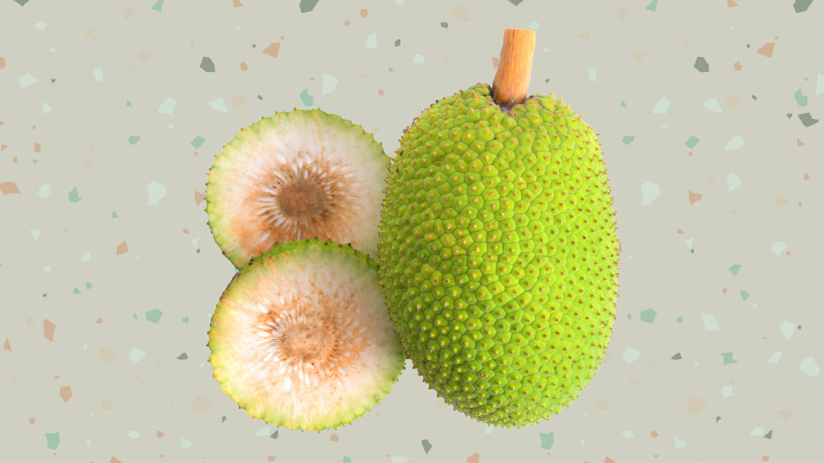 切片面包果——熱帶美味 壁紙 — 一個完整的帶刺綠色菠蘿蜜旁邊有兩半，露出淡奶油色的果肉，背景是斑點水磨石。