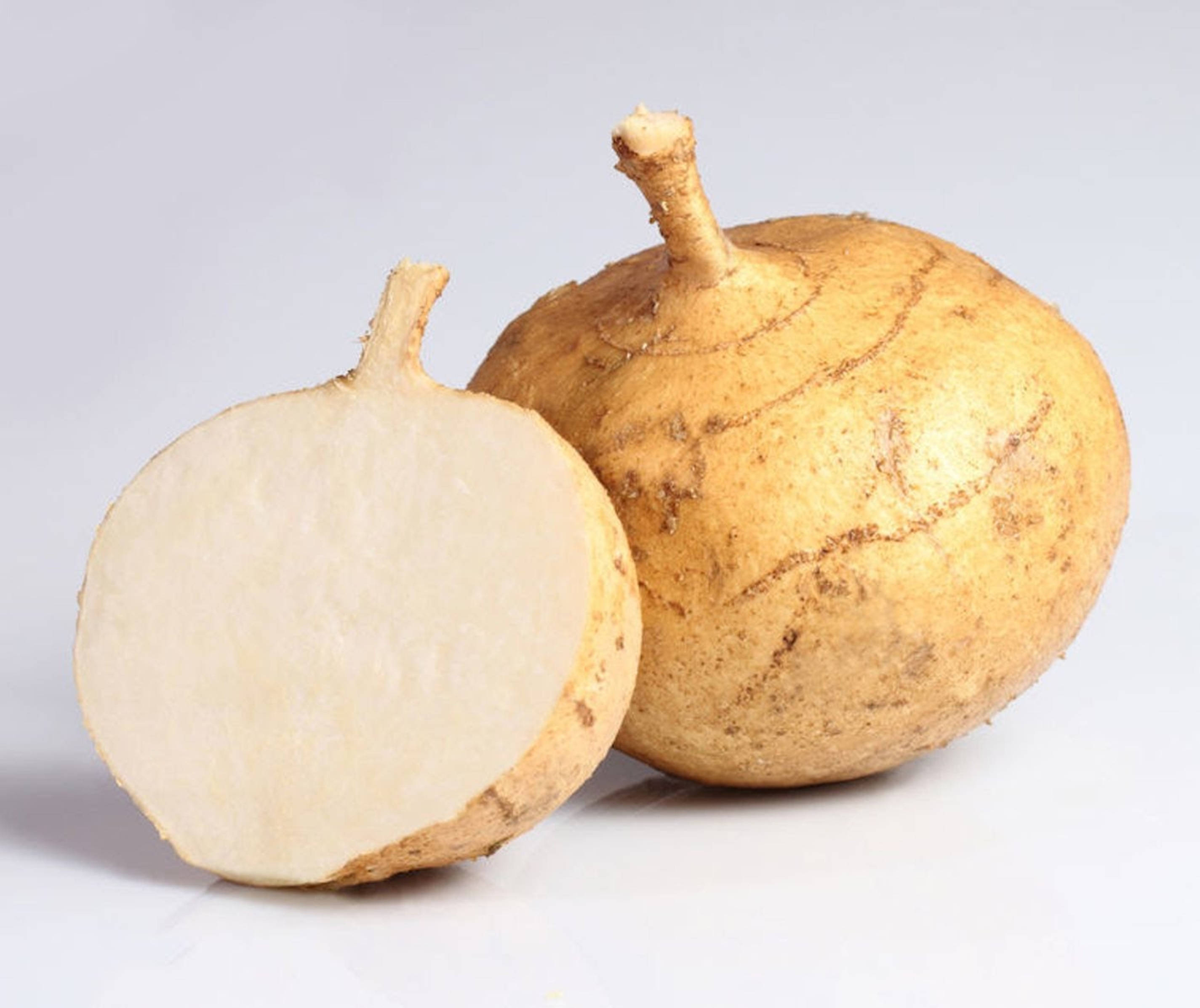 切開的地瓜（Jicama）擺放在木製砧板上 壁紙 — 一個完整和半切的黃褐色山藥根，帶有奶油白色的果肉，展示在乾淨的白色表面上。
