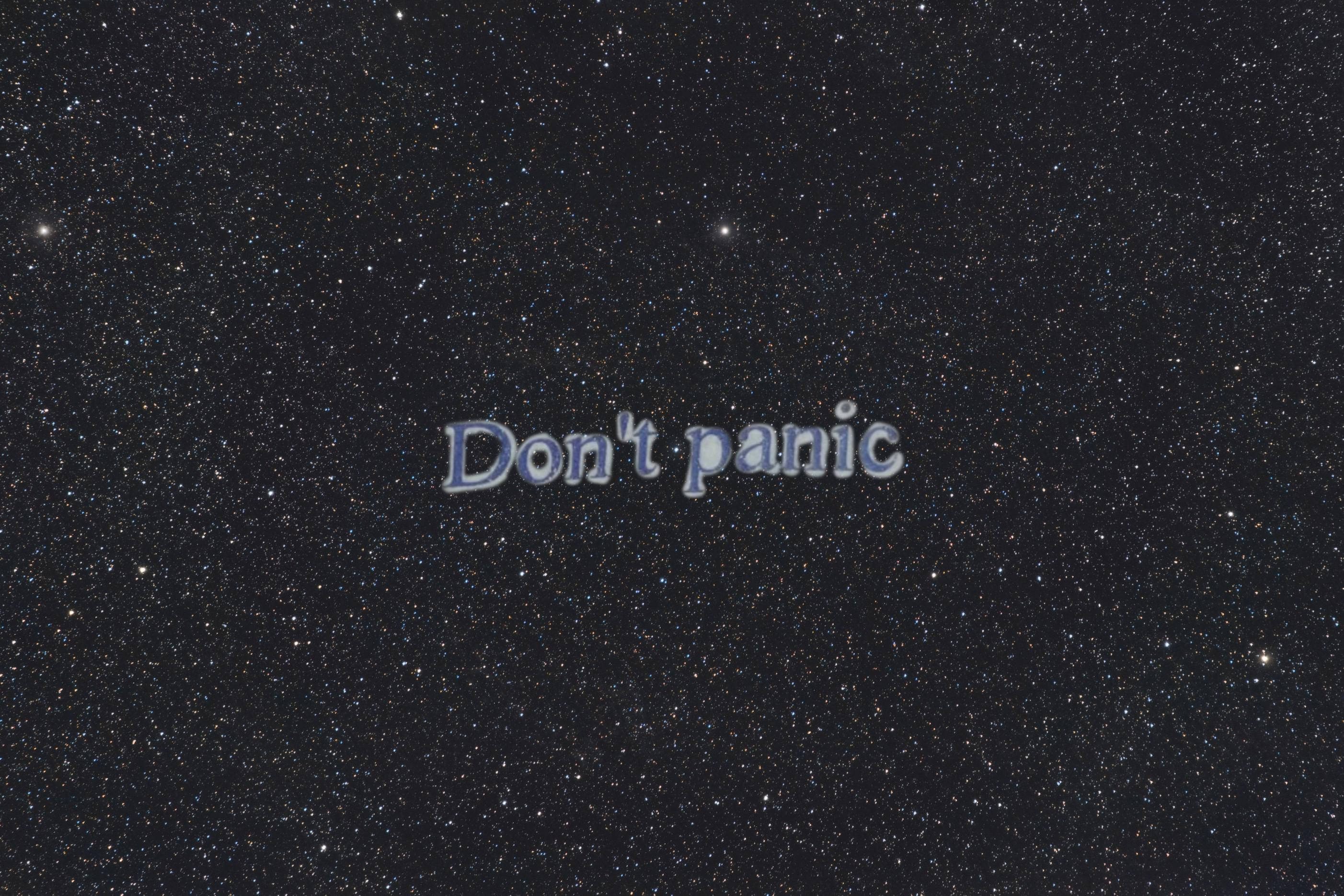 別慌星空背景 壁紙 — 「Don't panic」呢句短語漂浮喺一個充滿無數閃爍星星嘅星空夜空。