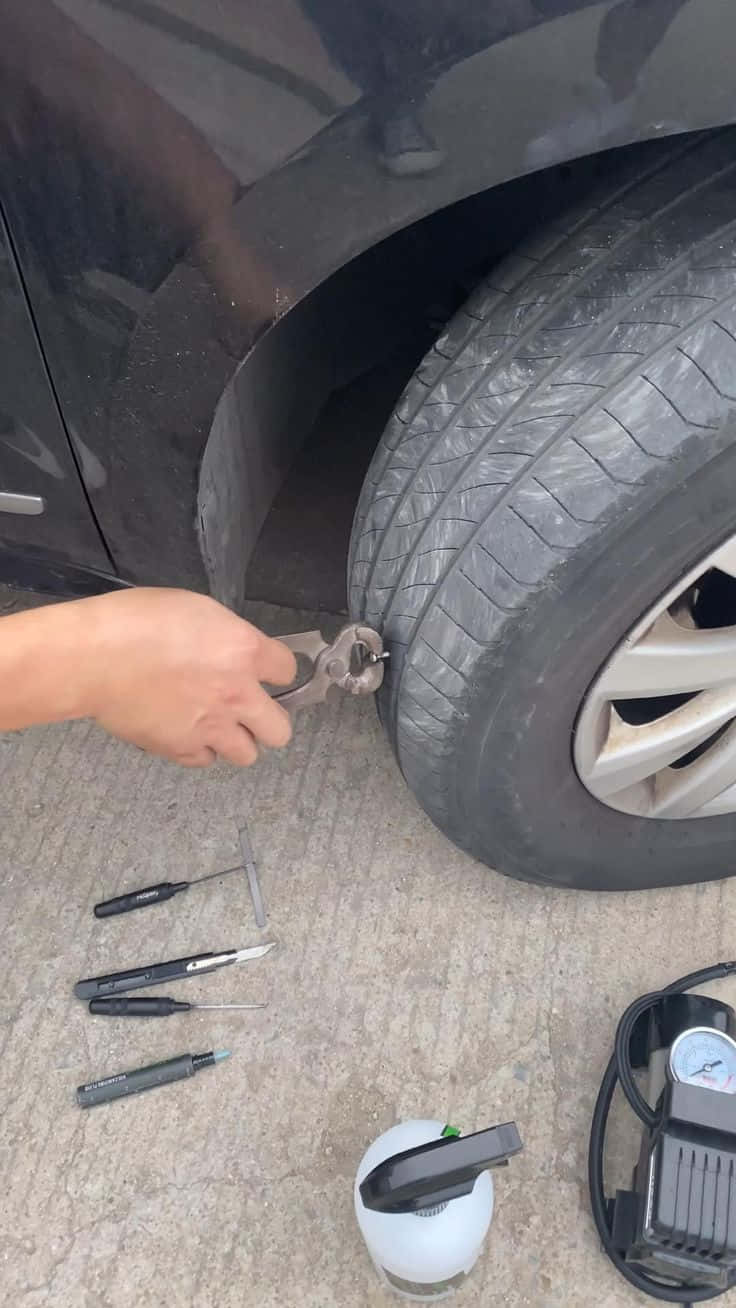 手在收緊汽車輪胎上的輪胎螺母，工具在地上