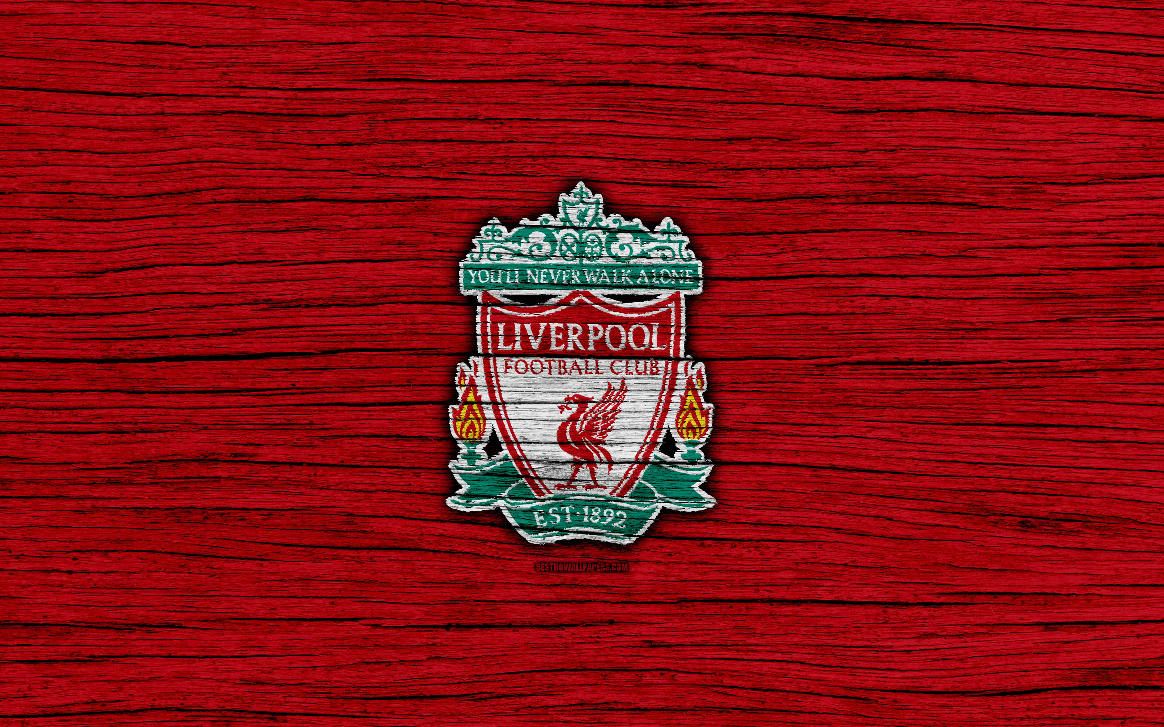 Liverpool Fc 桌布 壁紙 — 利物浦足球會徽章刺繡在帶有綠色點綴和火焰火炬的紋理紅色布料上。