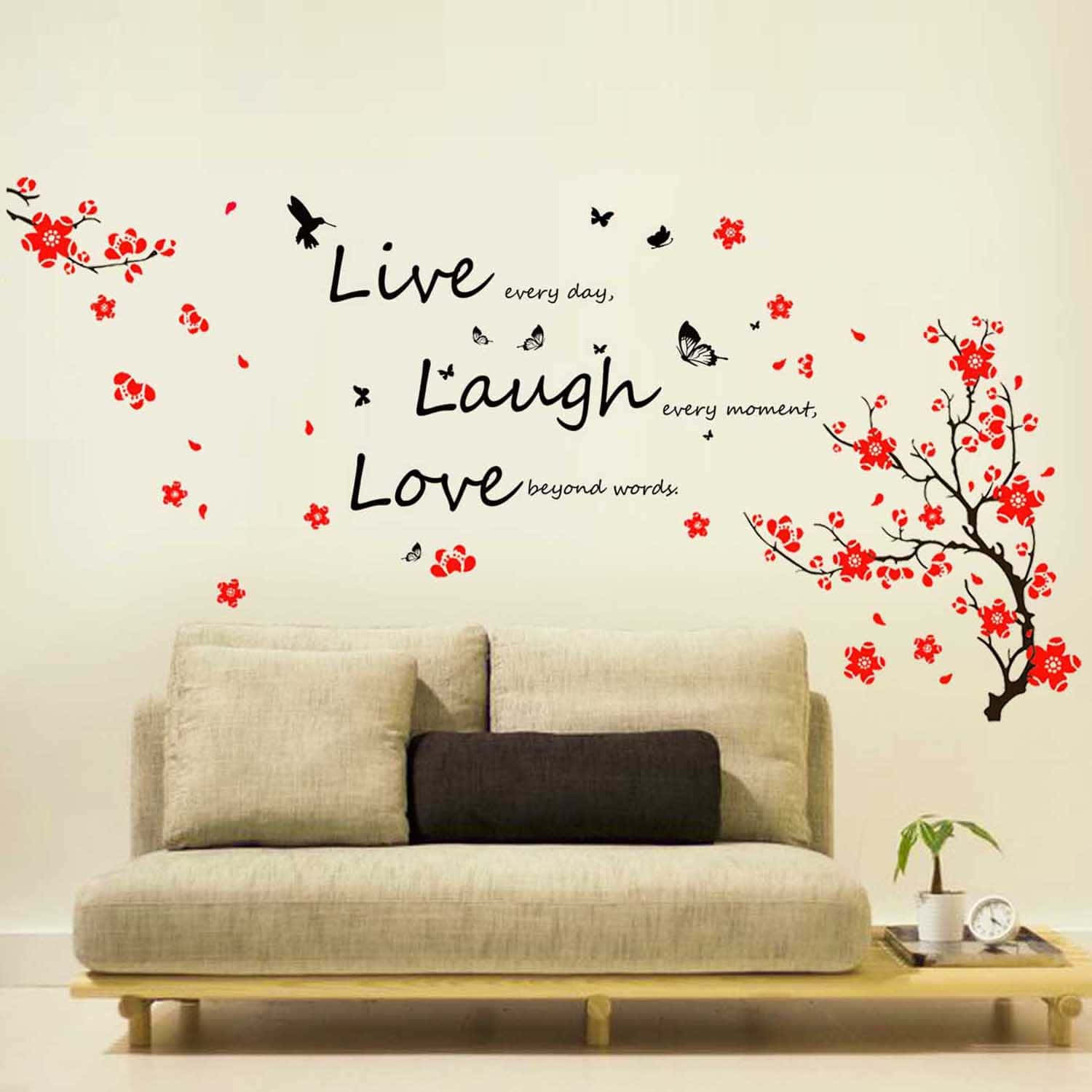 到處散播愛與喜悅 —— Live Laugh Love 壁紙 — 一張米色梳化放在牆貼下方，牆貼上有紅色櫻花、黑色雀鳥和流暢字體的「Live Laugh Love」。