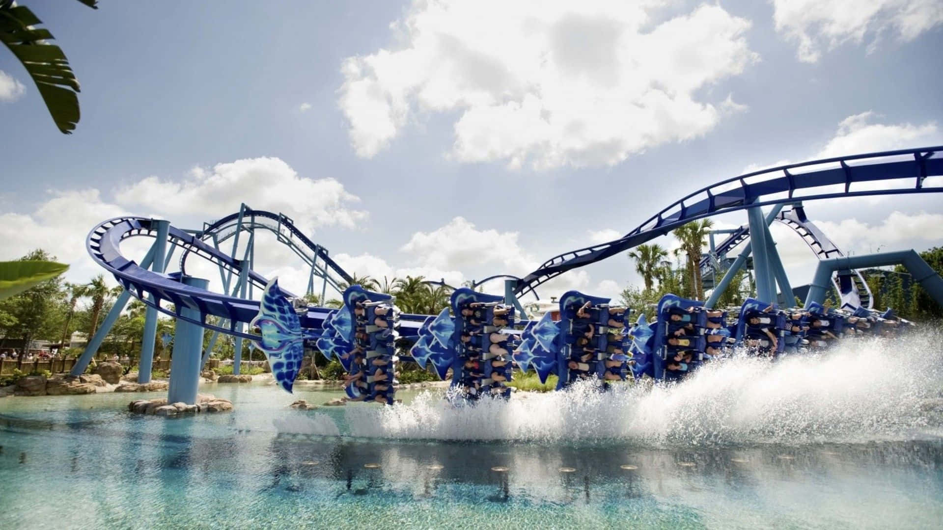 Roller Coaster 桌布 壁紙 — 刺激的藍色水上雲霄飛車將乘客衝入濺滿水花的泳池，天空晴朗明亮。