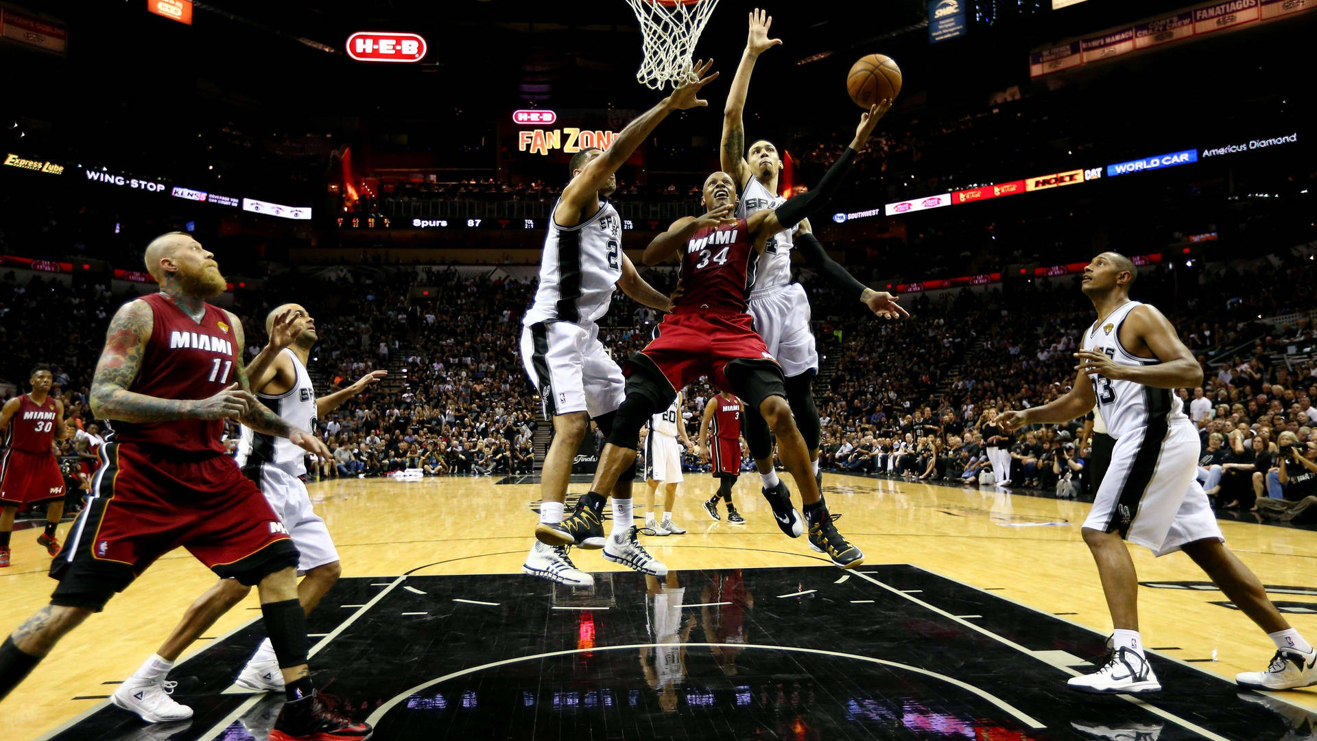 前NBA球星雷·阿倫 壁紙 — 一名邁阿密熱火球員在滿座的NBA比賽中跳向籃框，防守球員試圖封阻他的投籃。