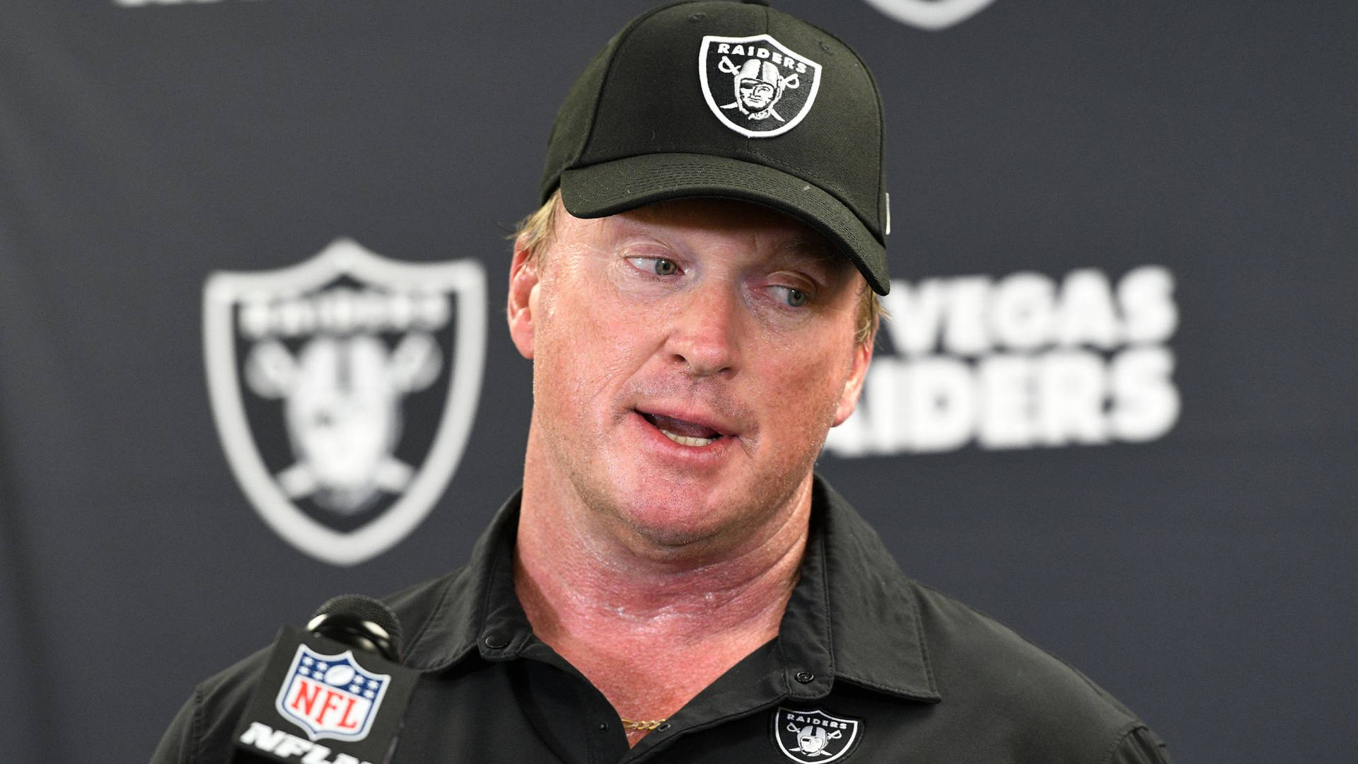 NFL教練穿著Raiders裝備在記者會上發言。