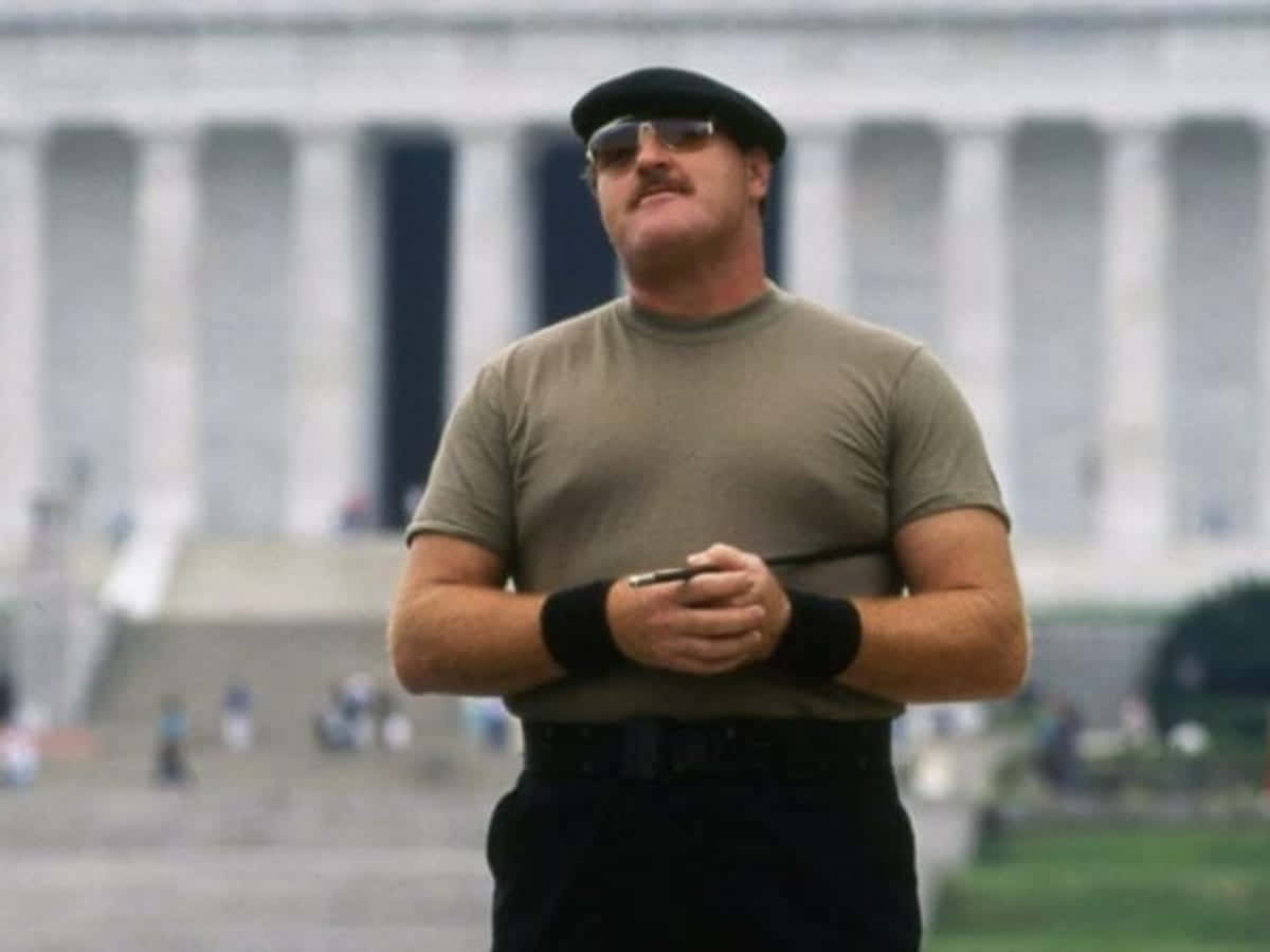 前摔角手兼海軍陸戰隊員Sgt Slaughter 壁紙 — 一位留鬍鬚、戴貝雷帽和太陽眼鏡的男子自信地站在林肯紀念堂前。