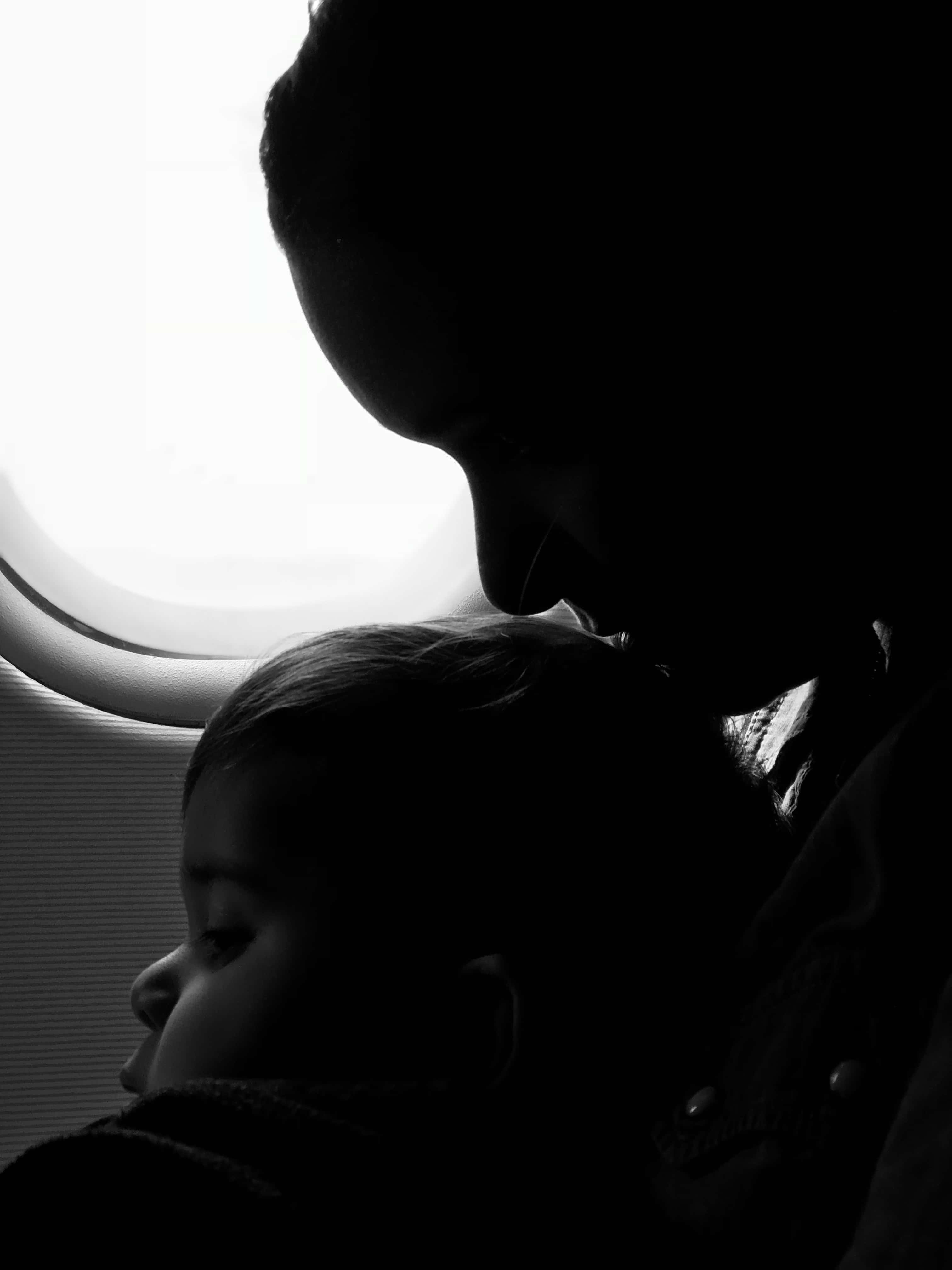 Dark Emotional 桌布 壁紙 — 剪影中的父母與孩子在飛機窗邊寧靜休息，高對比黑白。