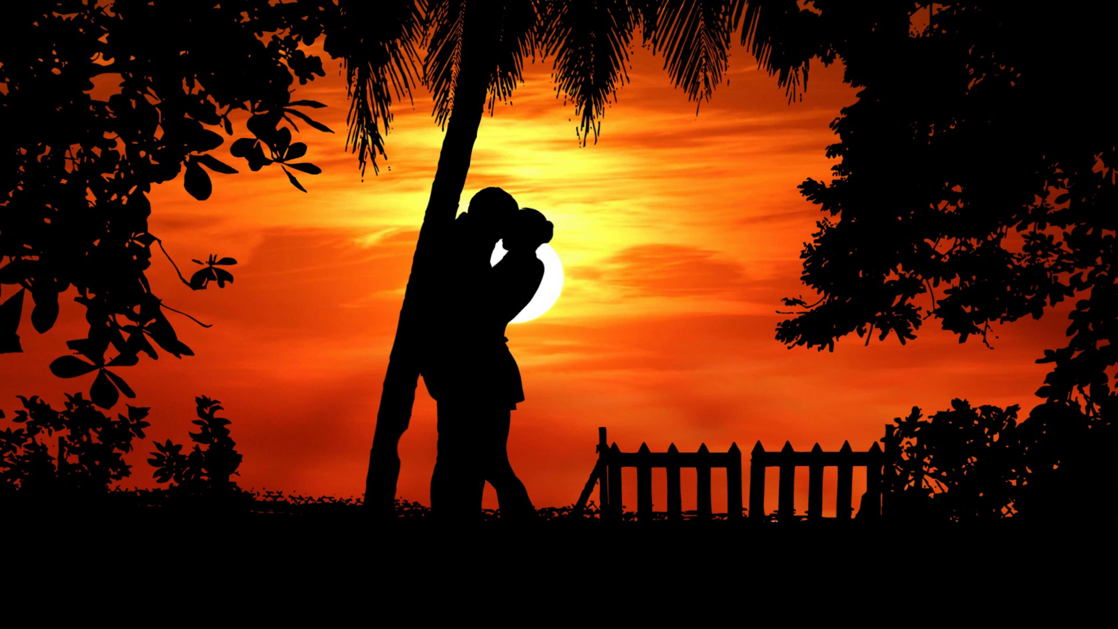 4K Love 桌布 壁紙 — 剪影情侶在棕櫚樹下擁抱，夕陽在他們身後燃燒成熾熱的橙色。