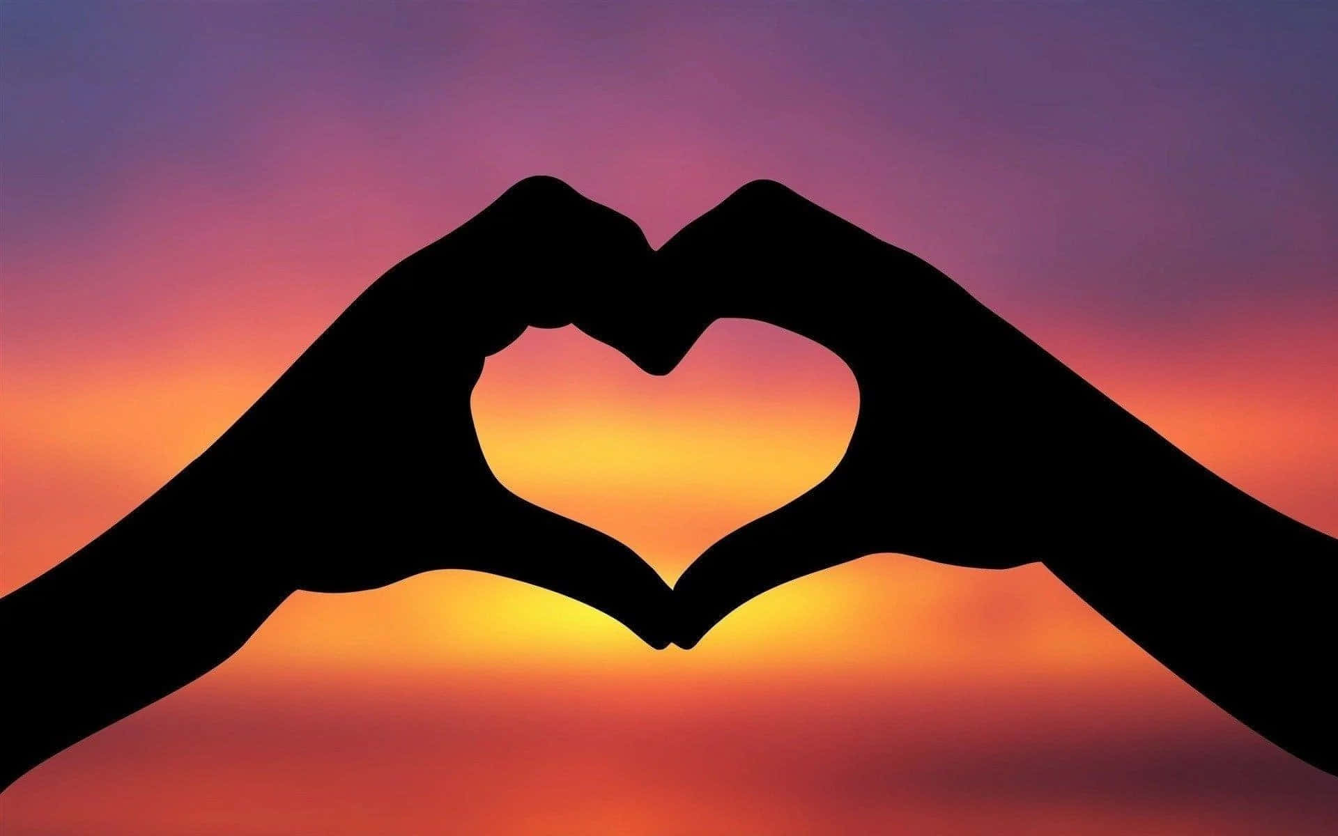 Heart Shape 桌布 壁紙 — 剪影手形在充滿活力的日落天空（混合橙色、粉紅色和紫色色調）中形成心形。