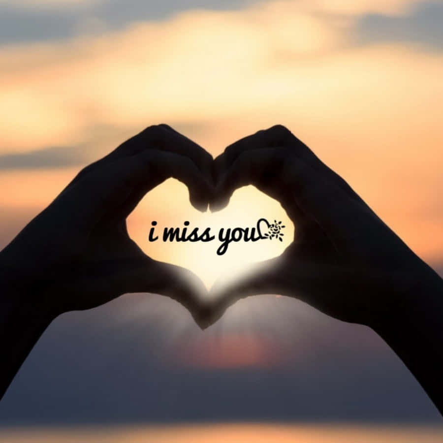 I Miss You 桌布 壁紙 — 剪影手形成心形，以「i miss you」文字框住太陽，背景是溫暖的日落天空。