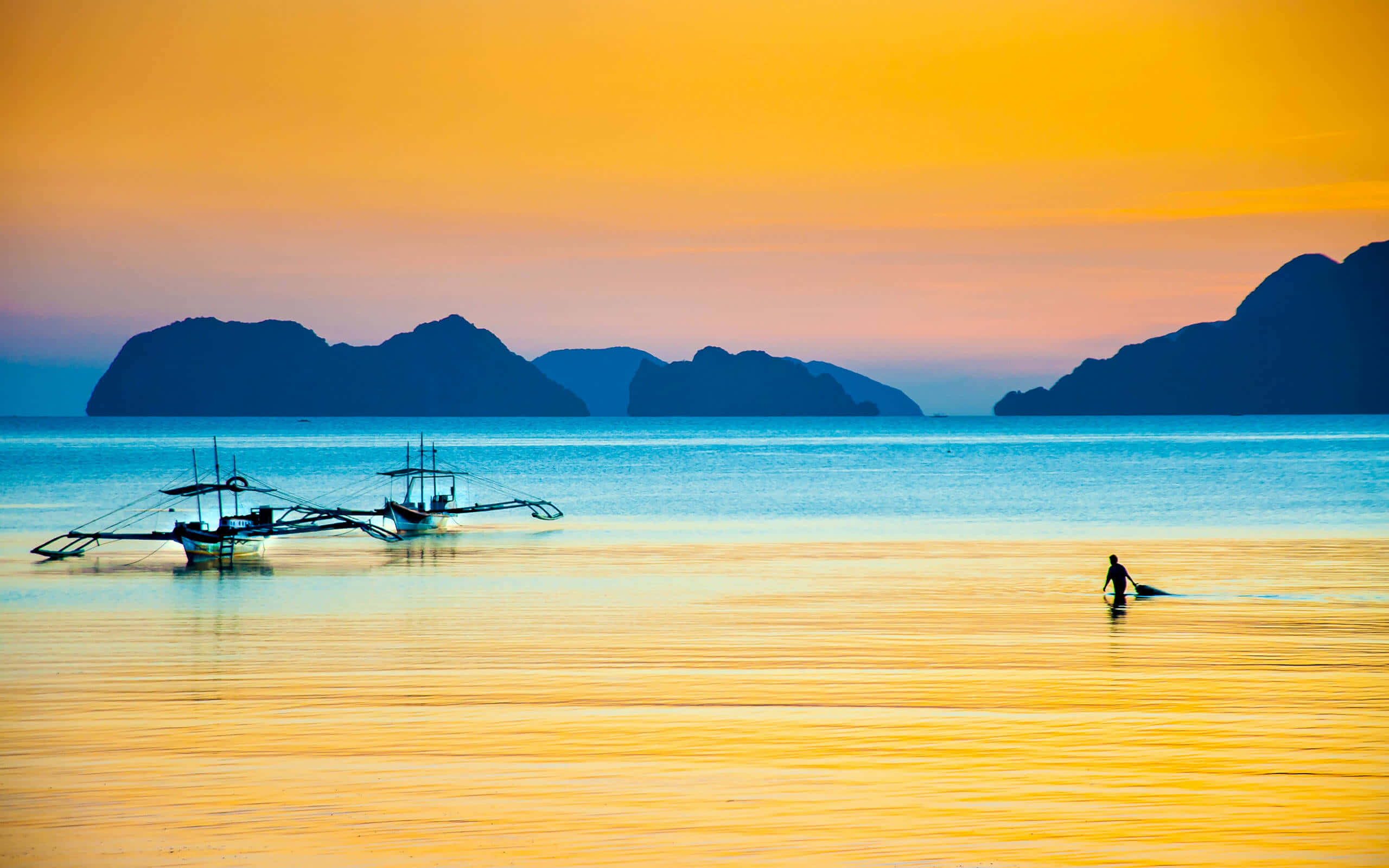 Philippines 桌布 壁紙 — 剪影的漁船和孤獨的漁夫站在夕陽下的金色淺灘上，遠方的火山島嶼在火紅的橙色天空下。