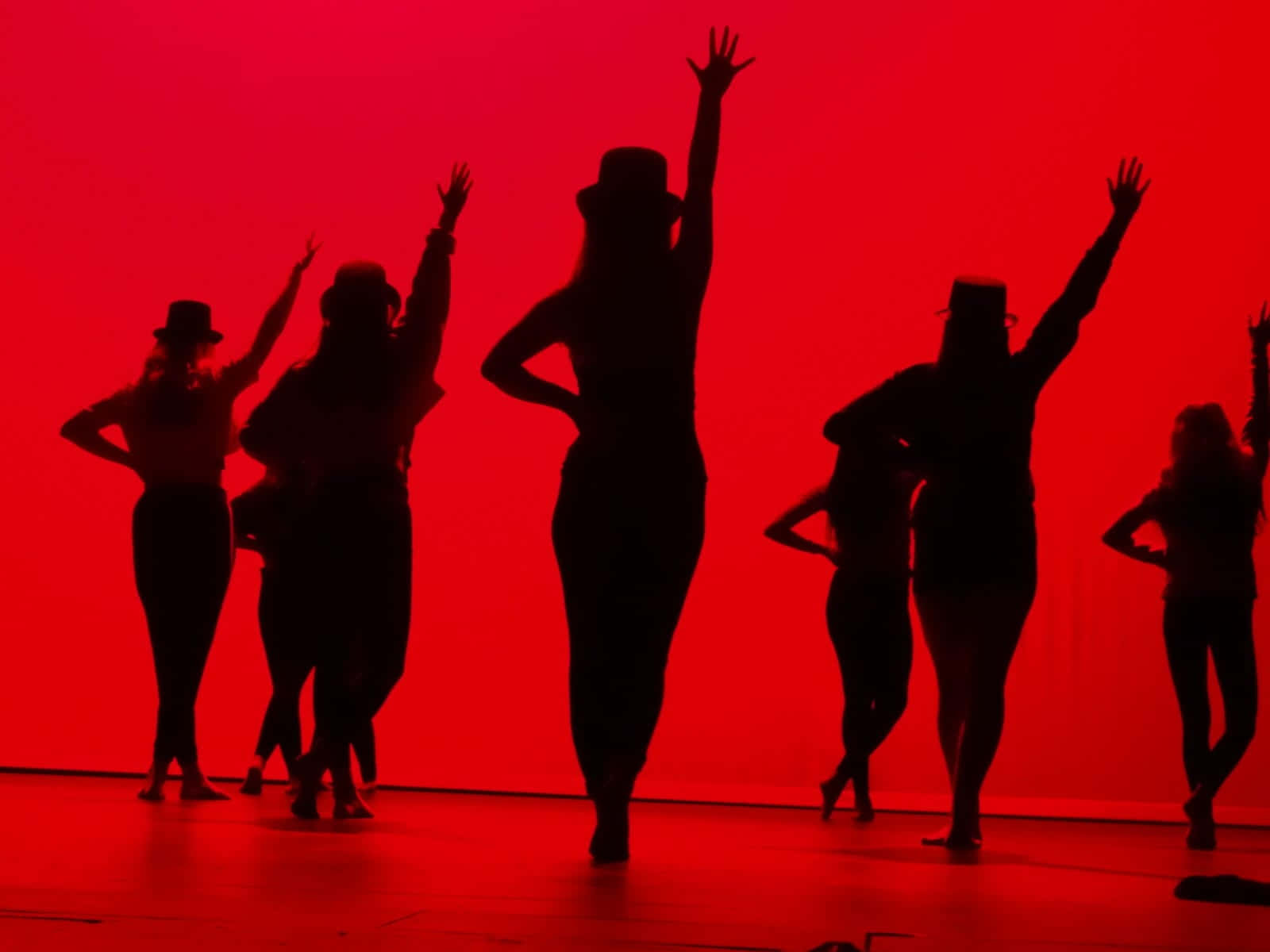 School Dance 桌布 壁紙 — 剪影舞者在戲劇性燈光下，以鮮紅色舞台背景襯托，擺出動感姿勢。